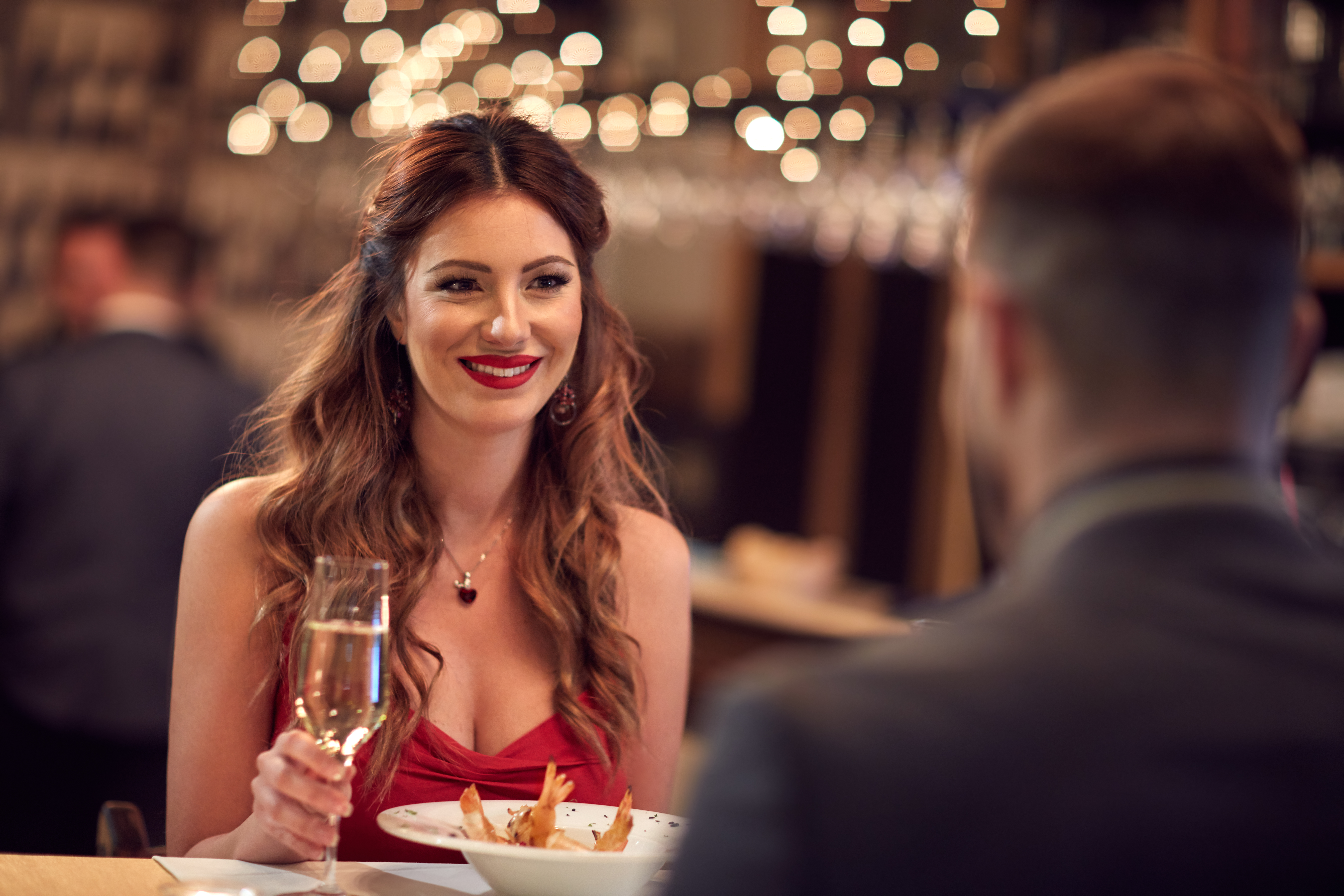 Frau im roten Kleid beim Abendessen mit ihrem Freund | Quelle: Shutterstock
