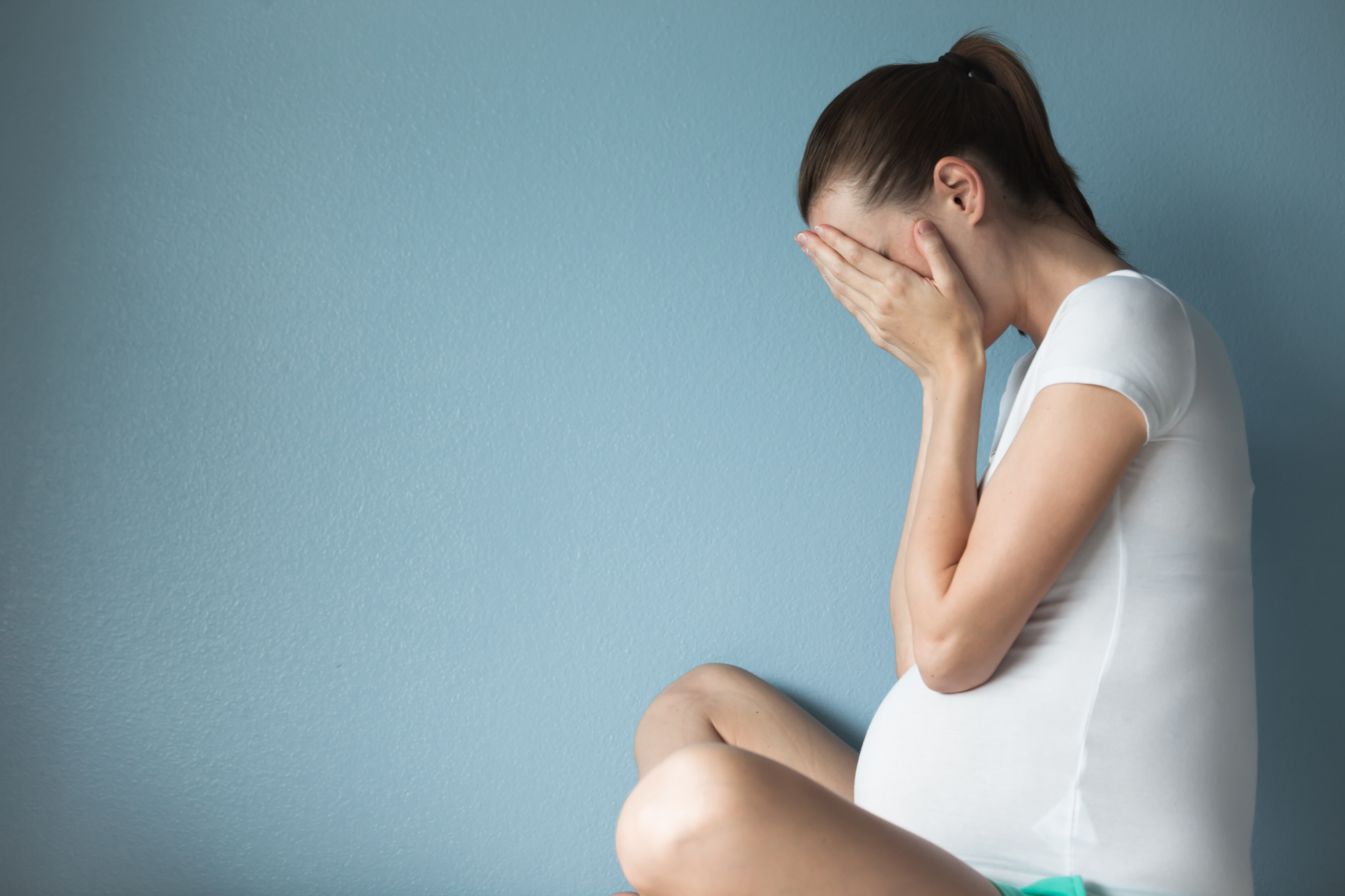 Eine schwangere Frau mit dem Kopf in ihren Händen | Quelle: Shutterstock