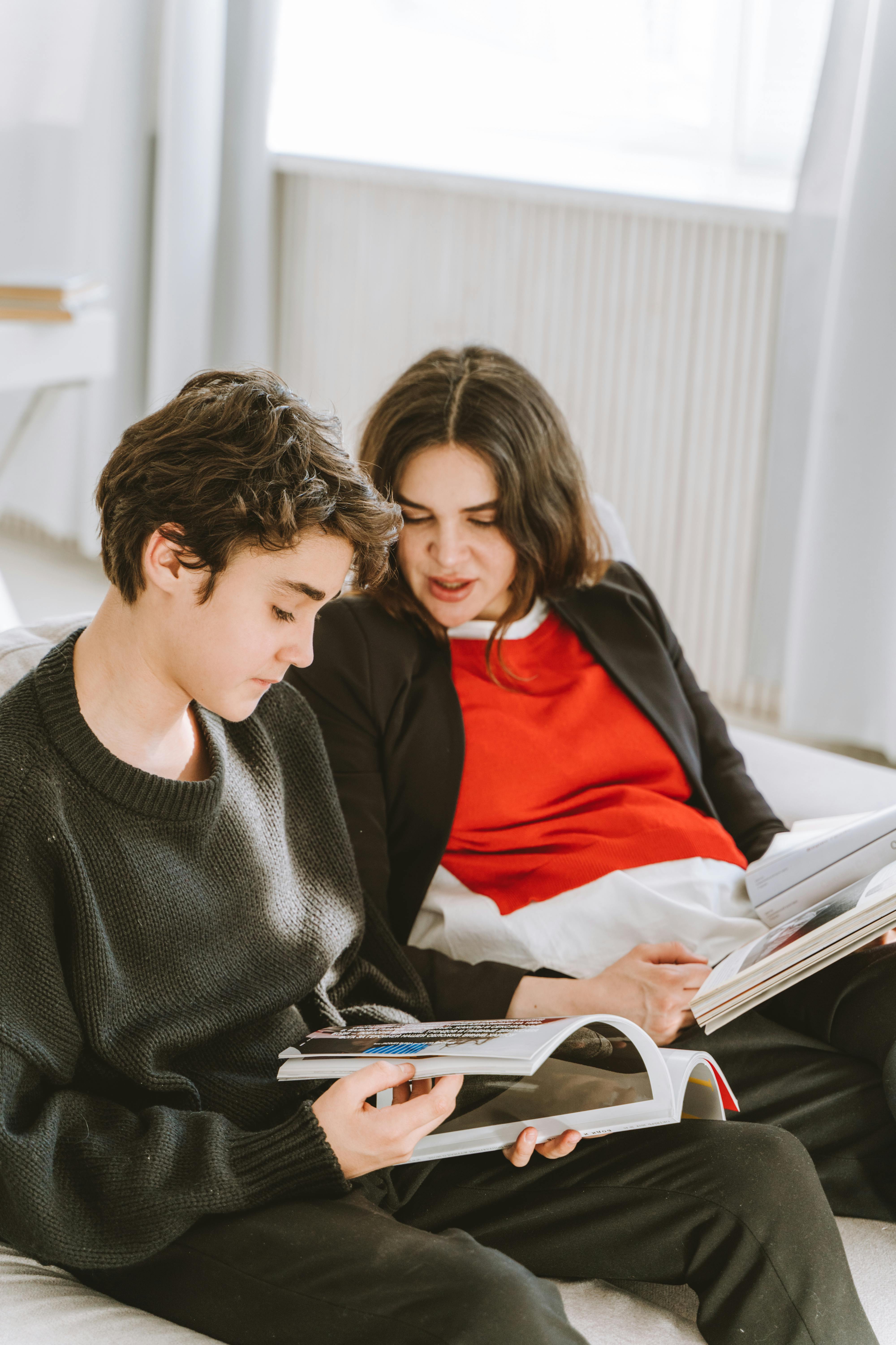 Eine Frau und ihr Sohn sitzen auf einer Couch und schauen sich Zeitschriften an | Quelle: Pexels