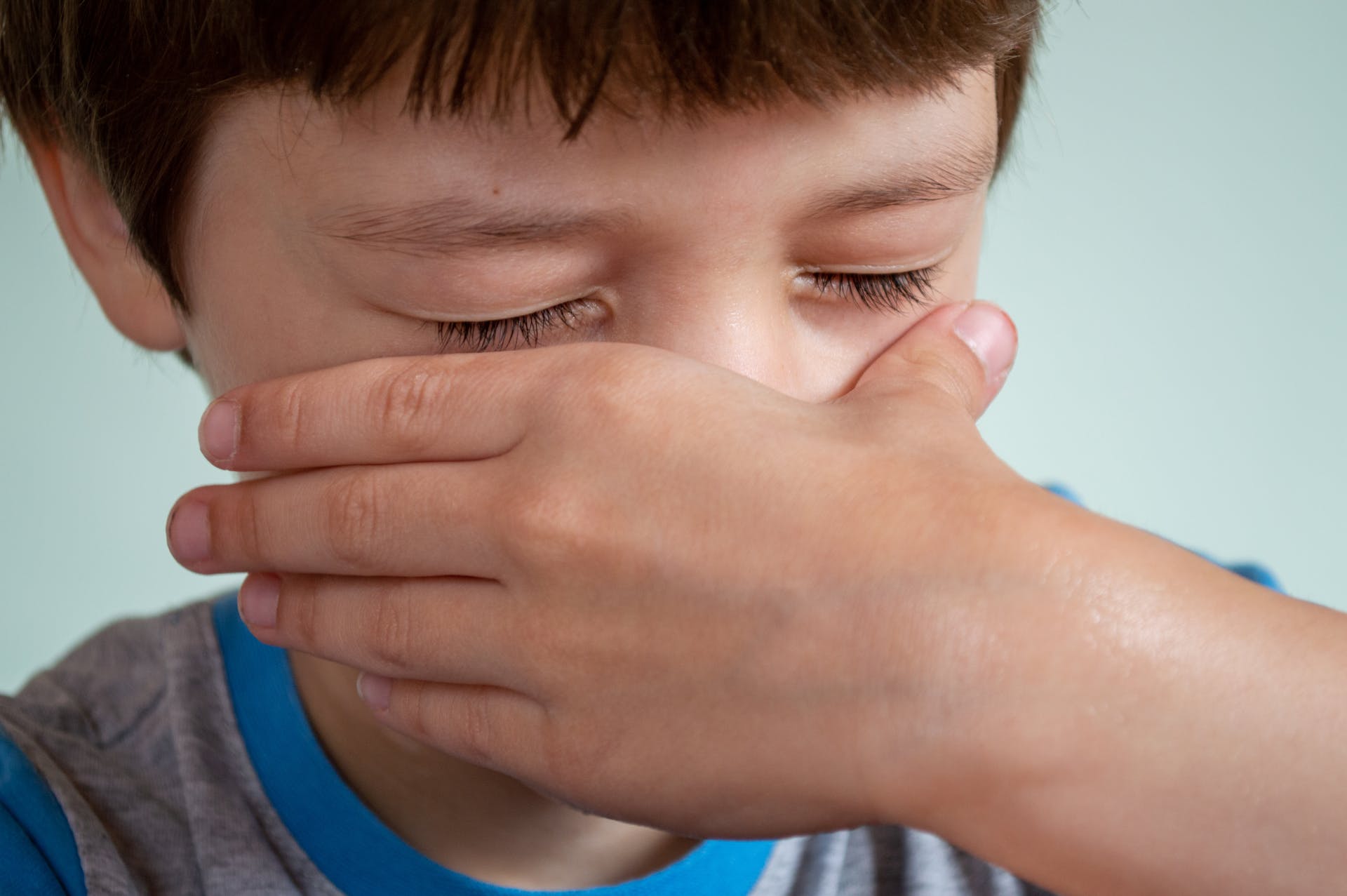 Ein Kind, das seine Nase mit der Hand abdeckt | Quelle: Pexels