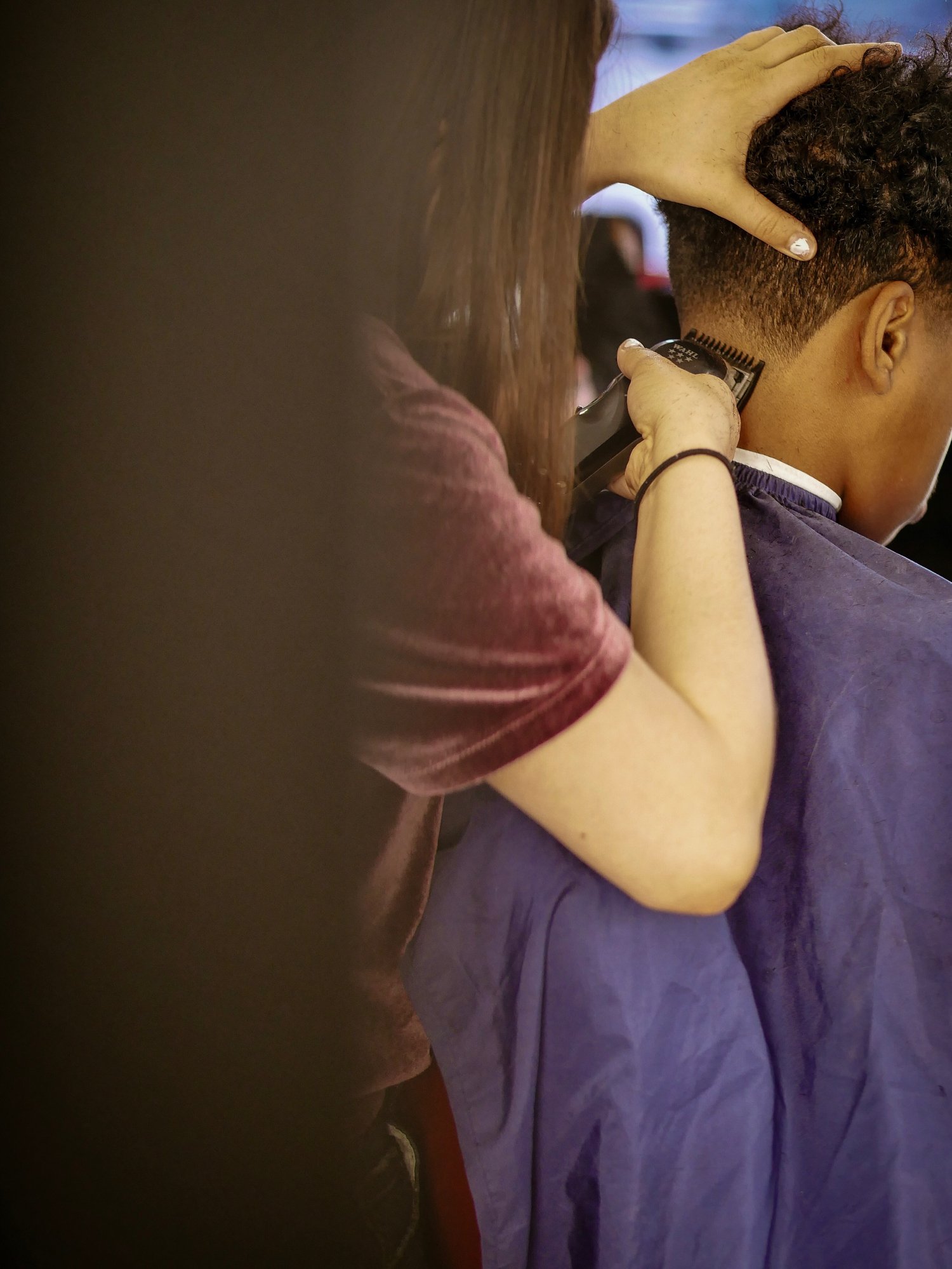 Frau rasiert den Kopf eines Jungen beim Friseur | Quelle: Getty Images