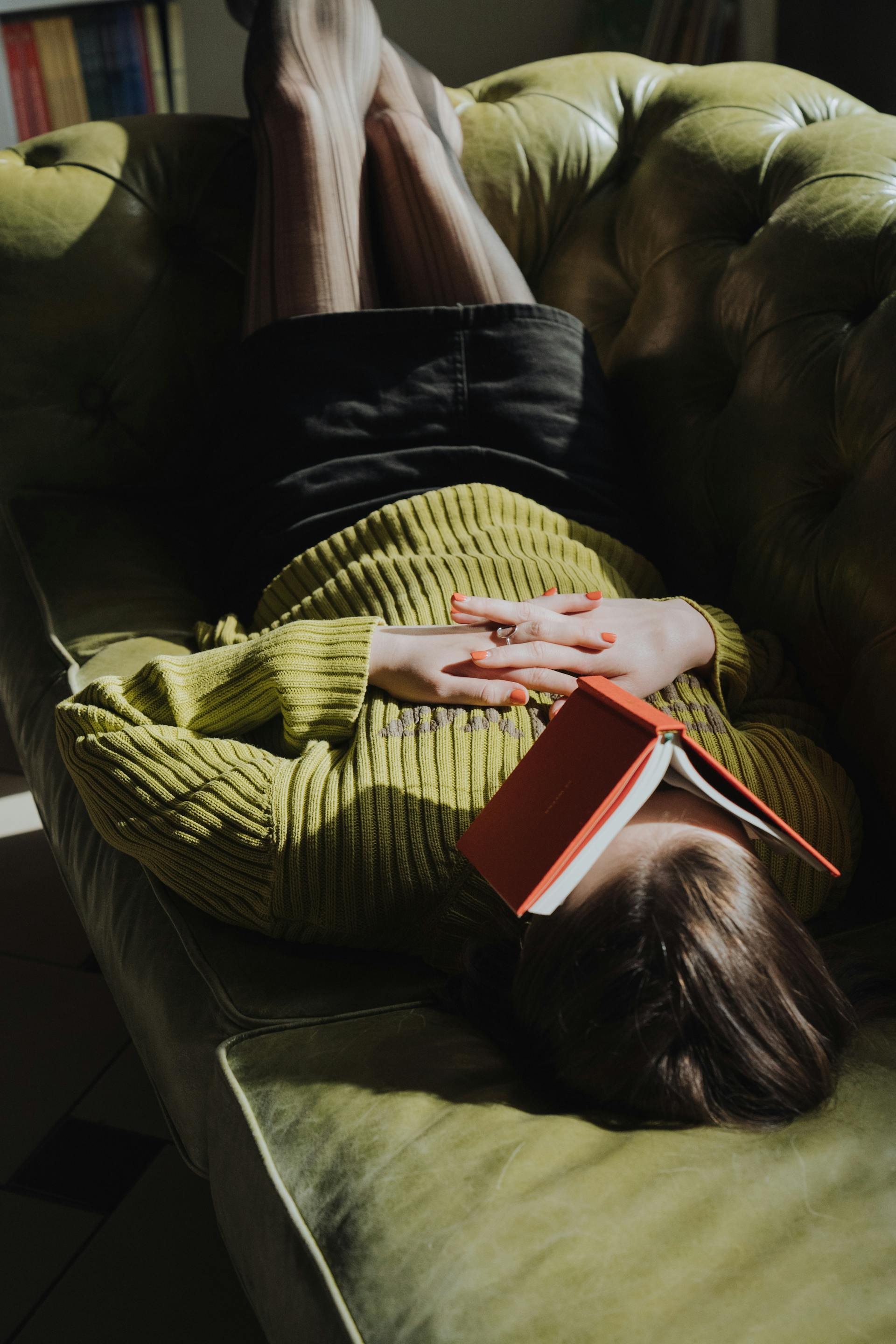 Eine Frau liegt mit einem Buch auf einer Couch | Quelle: Pexels