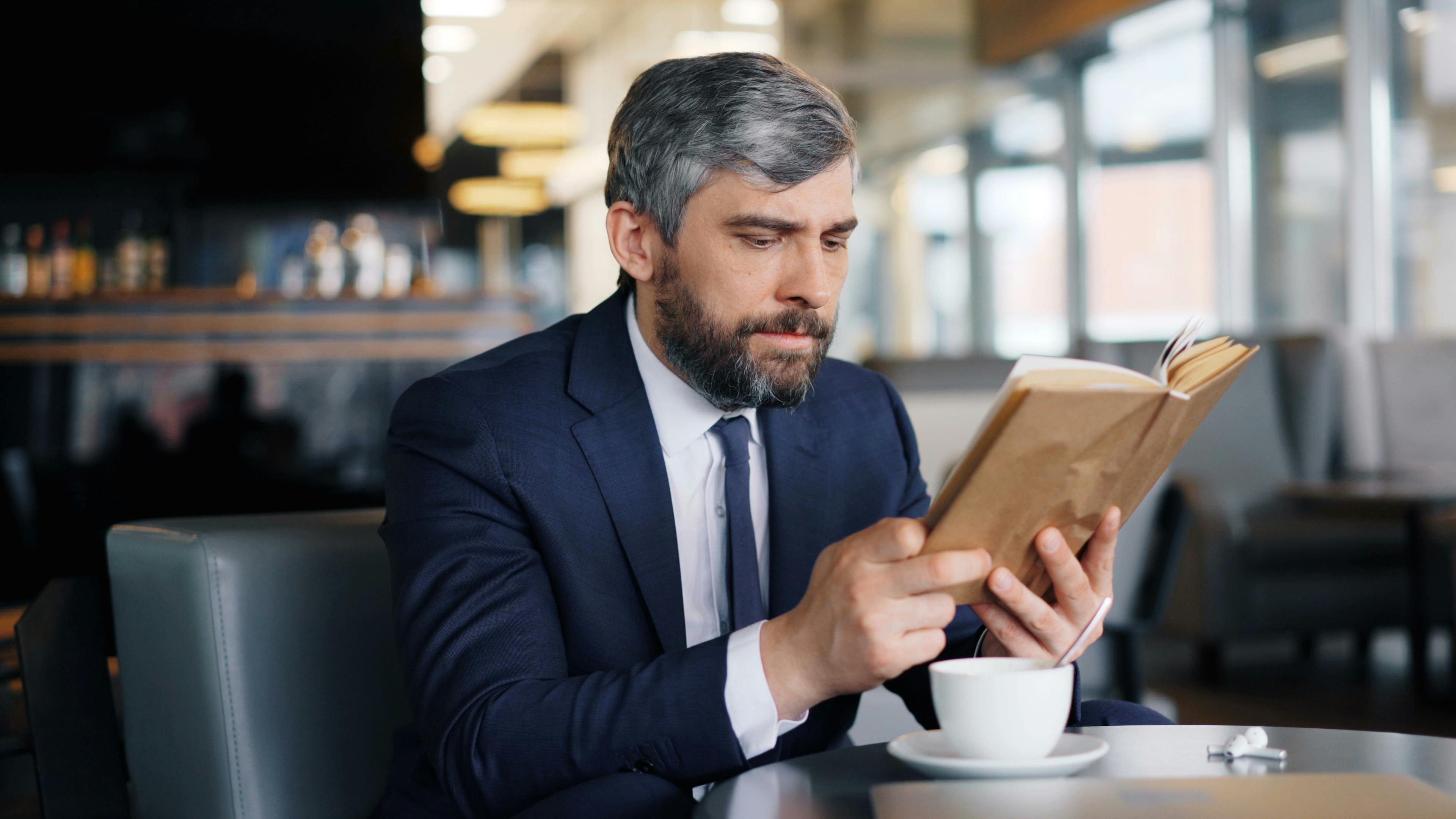 Ein Mann mit einem Buch in einem Cafe | Quelle: Pexels