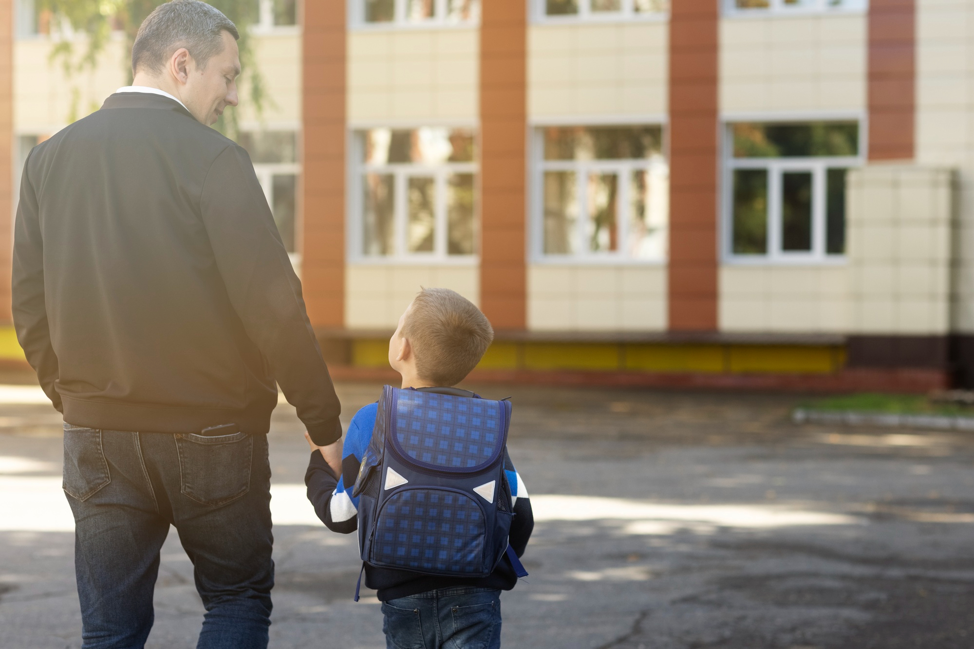 Ein kleiner Junge mit einem Rucksack, der seinen Vater anschaut | Quelle: Freepik