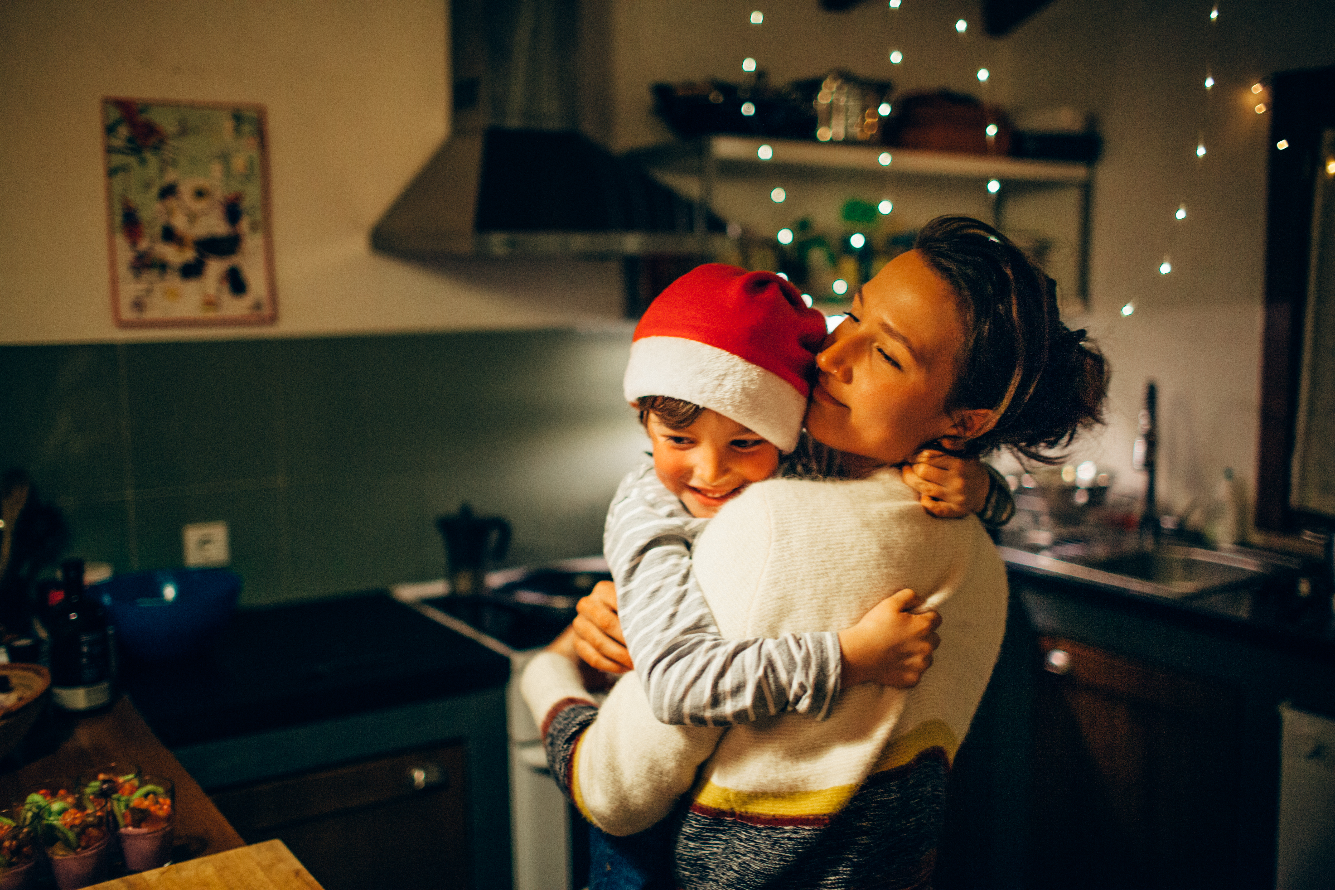 Mutter und Sohn umarmen sich in der Küche an Weihnachten | Quelle: Getty Images
