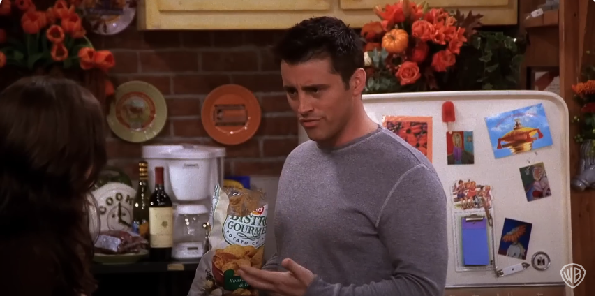 Matt Leblanc als Joey hält eine Packung Kartoffelchips am Set von "Friends" | Quelle: YouTube/@warnerbrostv