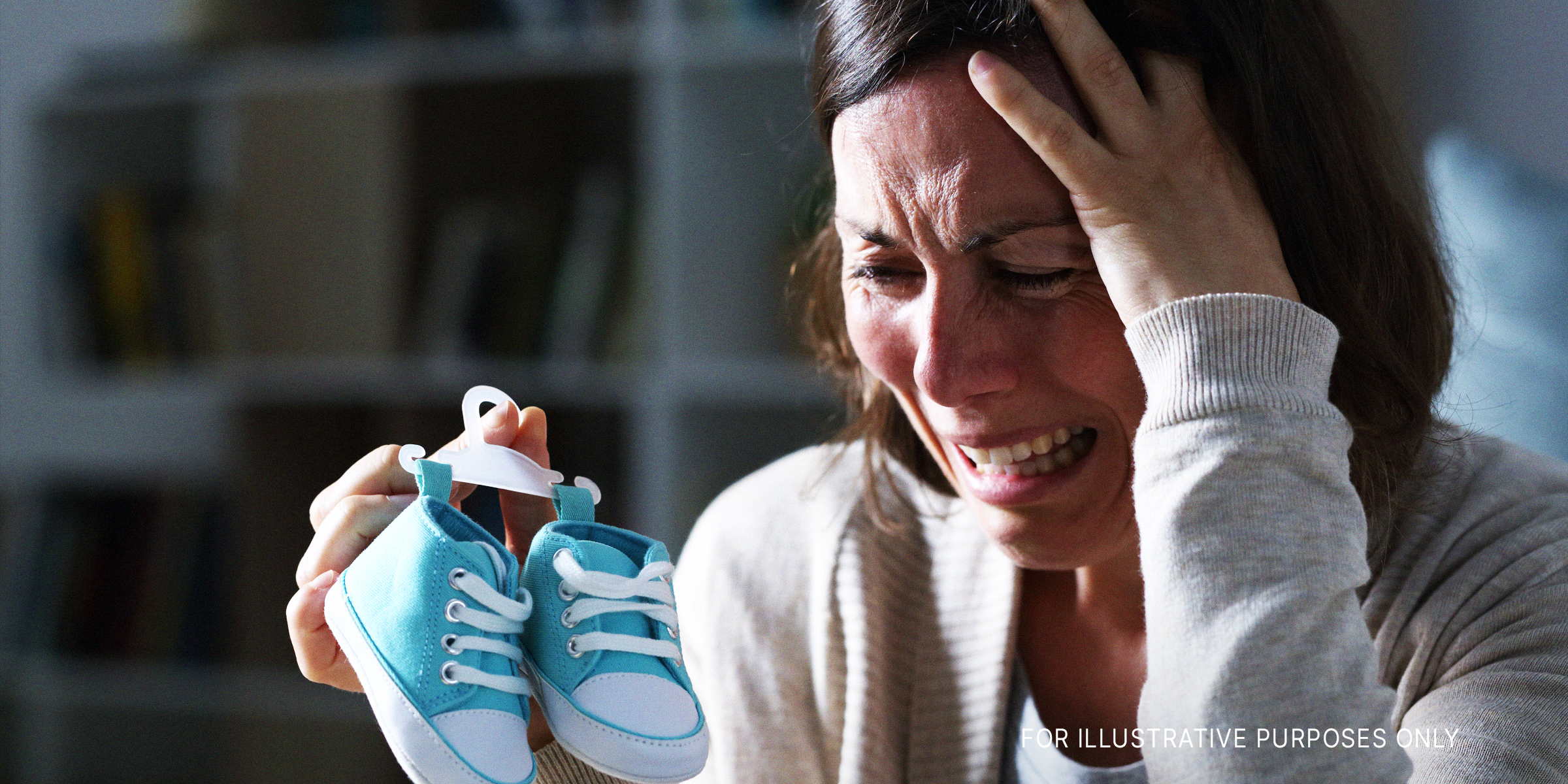 Eine weinende Frau, die Babyschuhe hält | Quelle: Shutterstock