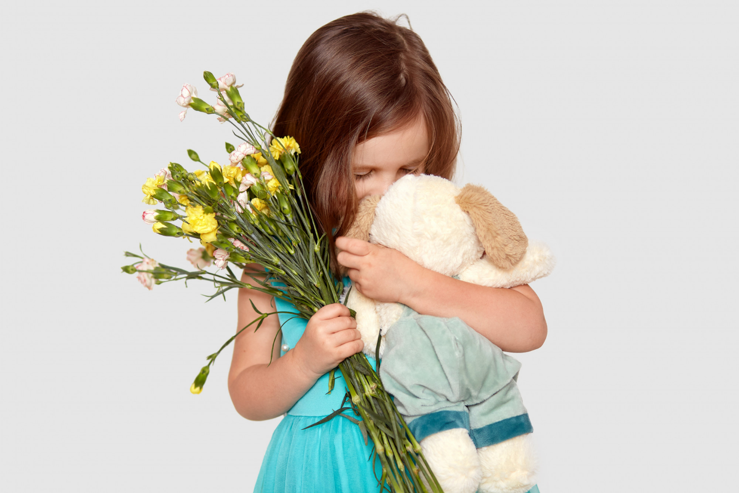Ein trauriges kleines Mädchen hält ihr Stofftier und Blumen in der Hand | Quelle: Freepik