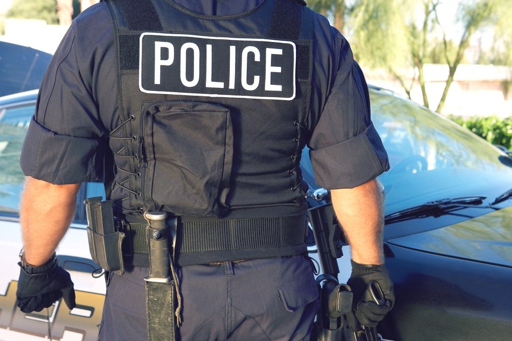 Ein Polizist steht neben einem Auto. | Quelle: Shutterstock