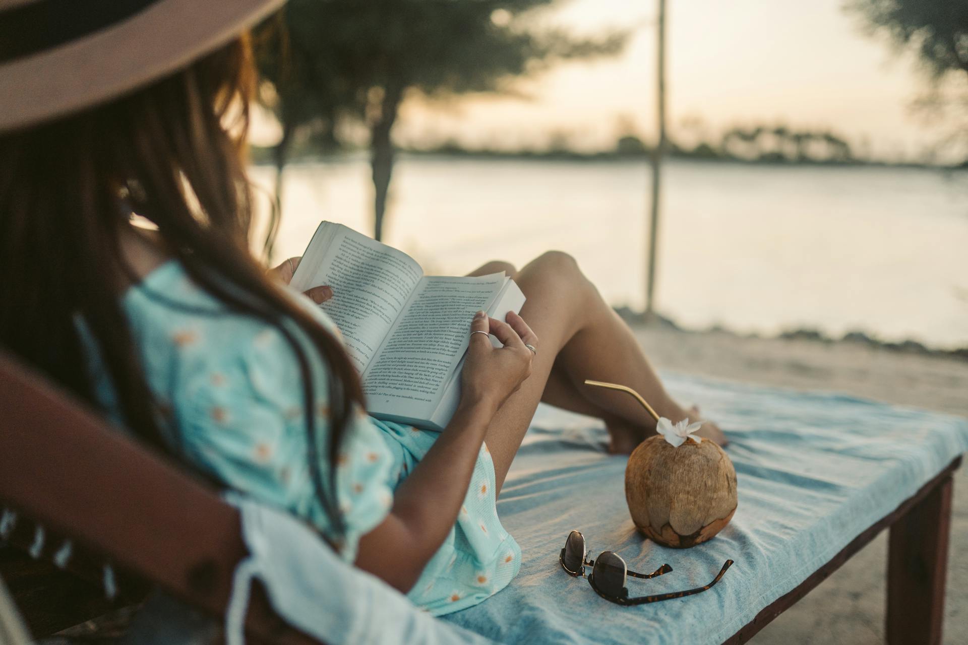 Eine Frau liegt auf einem Liegestuhl und liest ein Buch | Quelle: Pexels