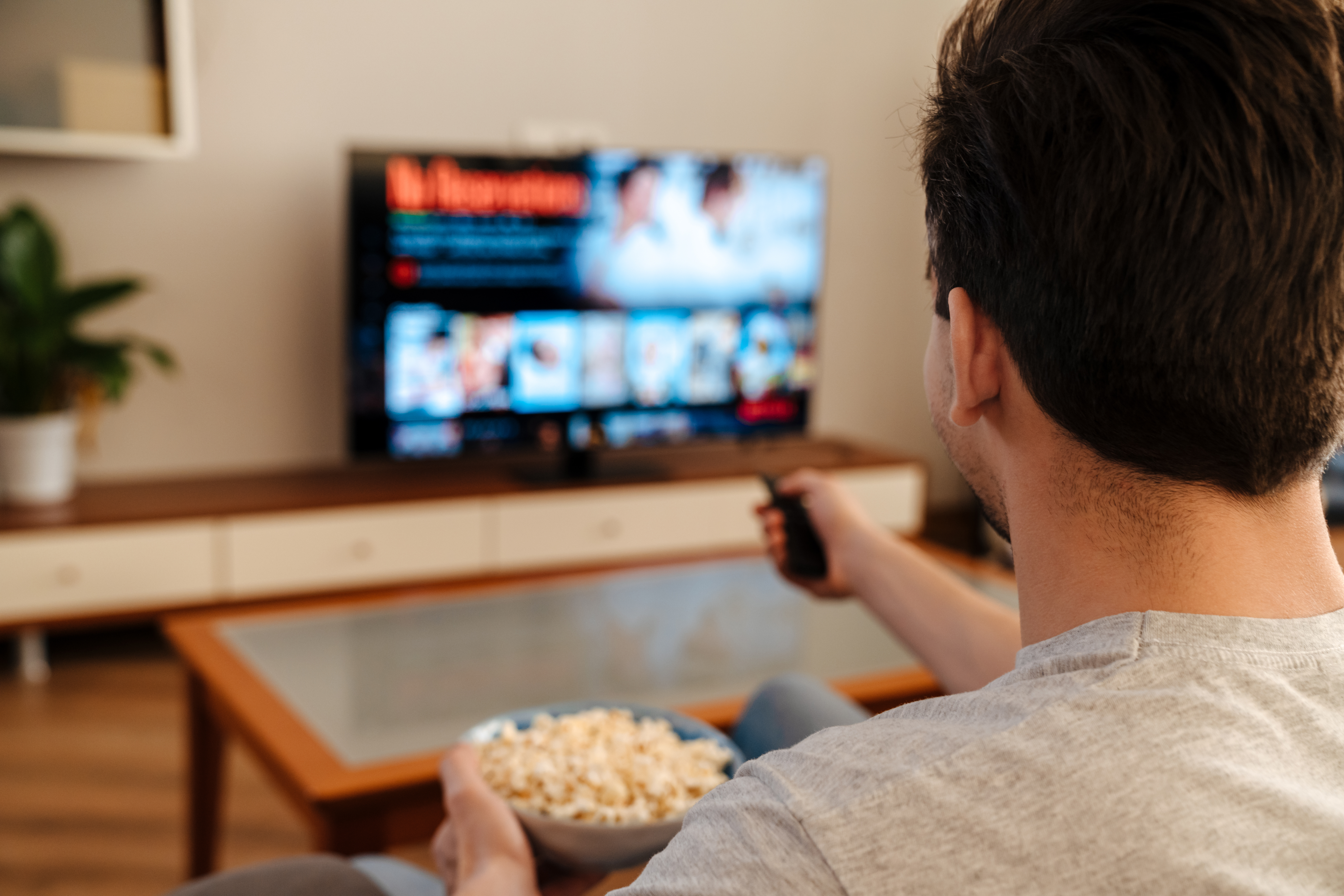 Ein Mann, der zu Hause fernsieht und Popcorn isst | Quelle: Shutterstock