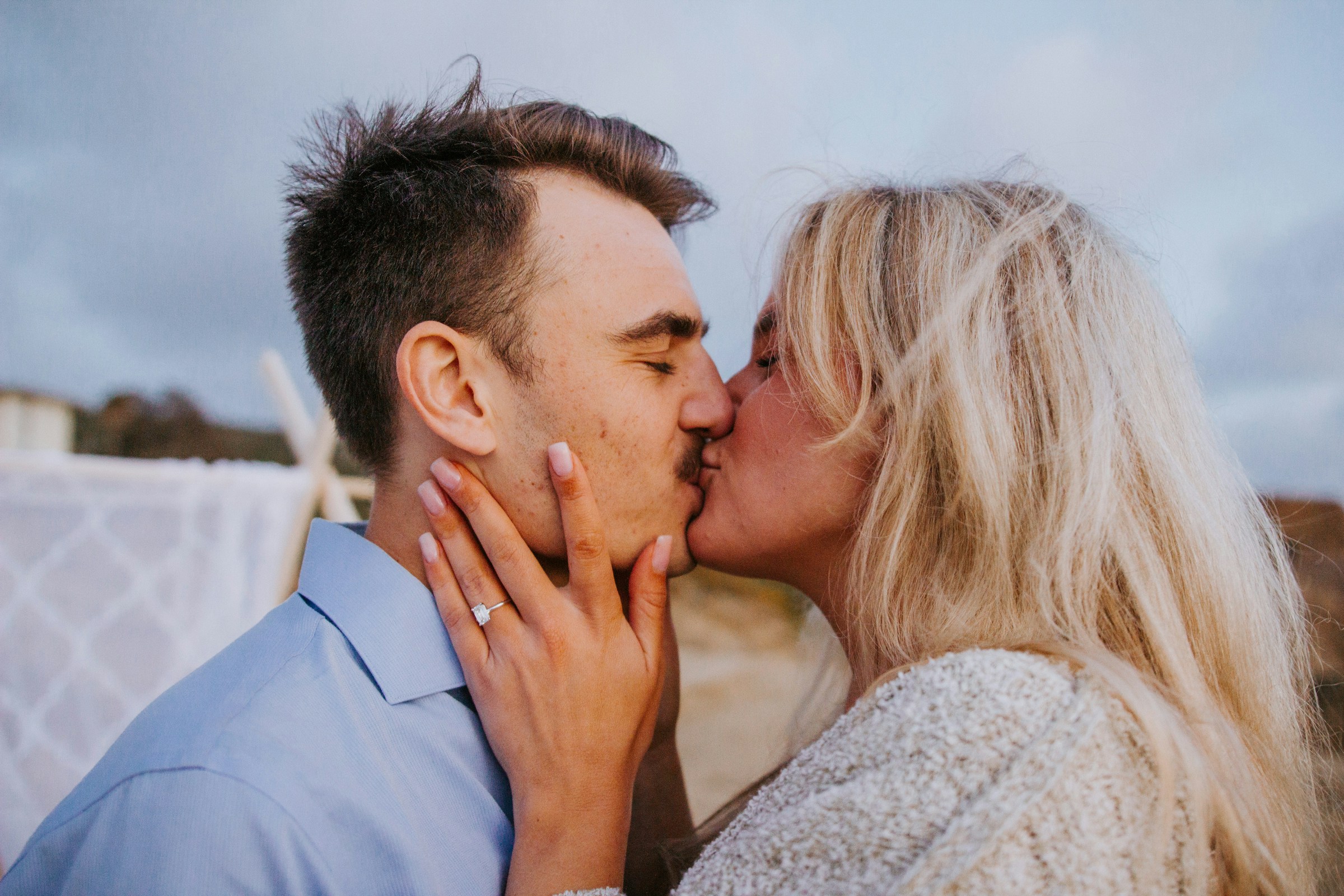 Ein Paar, das sich küsst und seinen Verlobungsring zeigt | Quelle: Unsplash