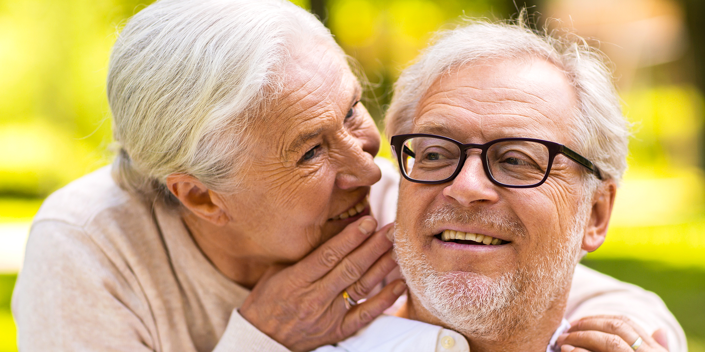 Eine ältere Frau, die ihrem Mann etwas zuflüstert | Quelle: Shutterstock