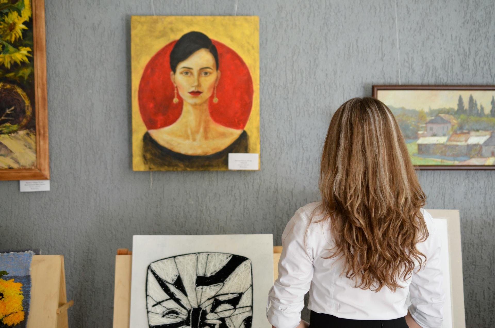 Eine junge Frau betrachtet die Gemälde an einer Wand | Quelle: Pexels