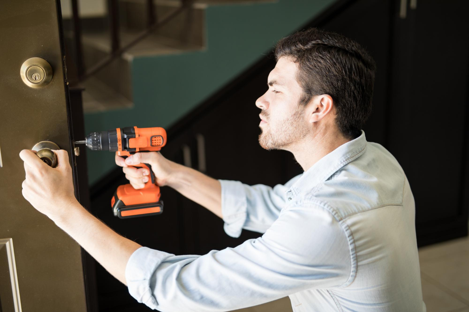 Ein Handwerker benutzt eine Bohrmaschine, um einen Türknauf zu reparieren | Quelle: Freepik