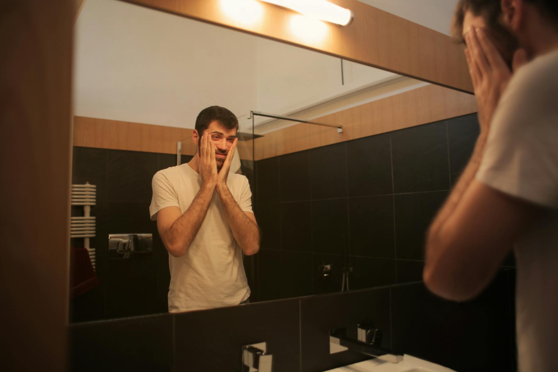 Ein müder Mann, der in einem Badezimmer in den Spiegel schaut | Quelle: Pexels
