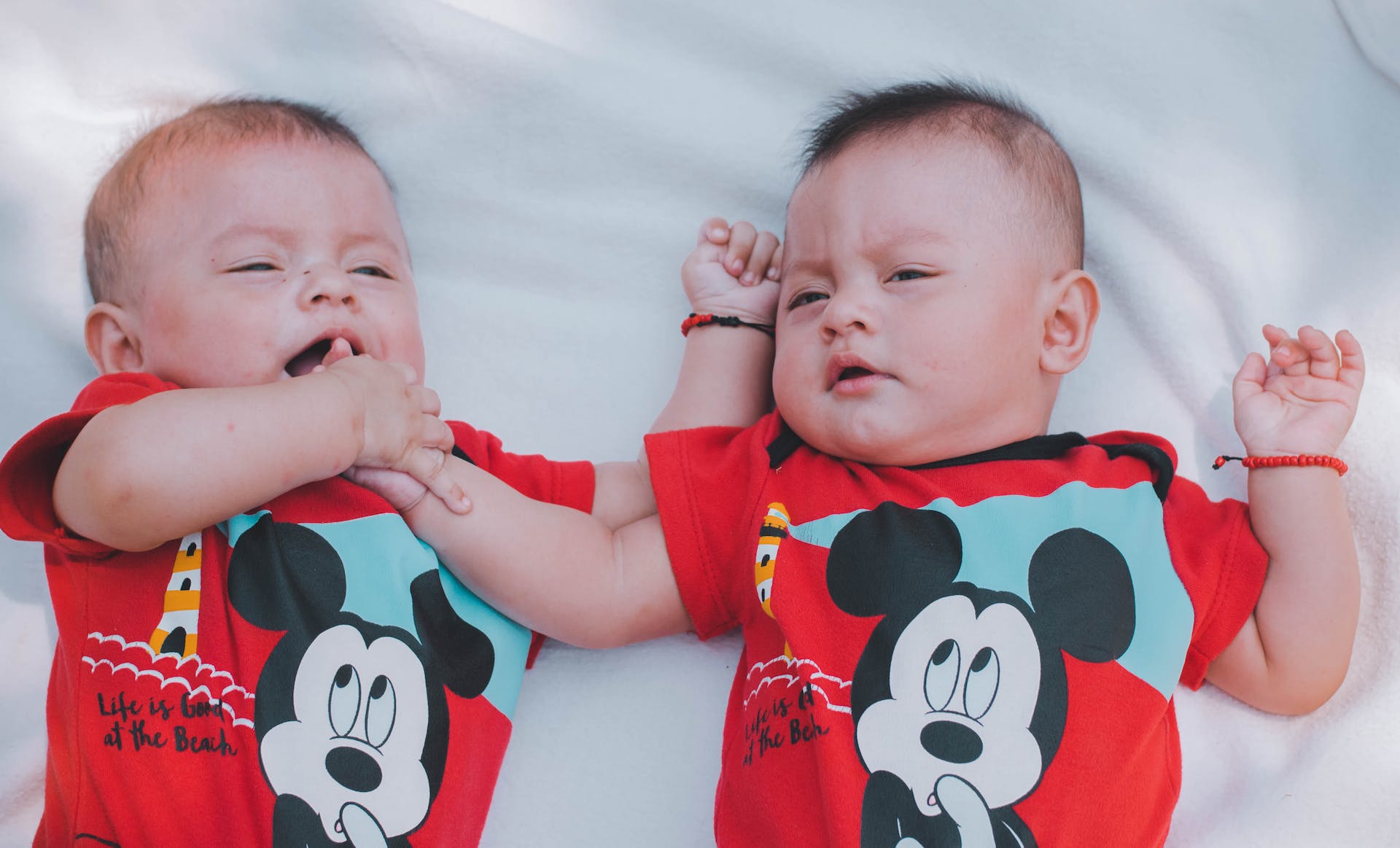 Zwei Babys in roten Mickey Mouse-Shirts | Quelle: Pexels