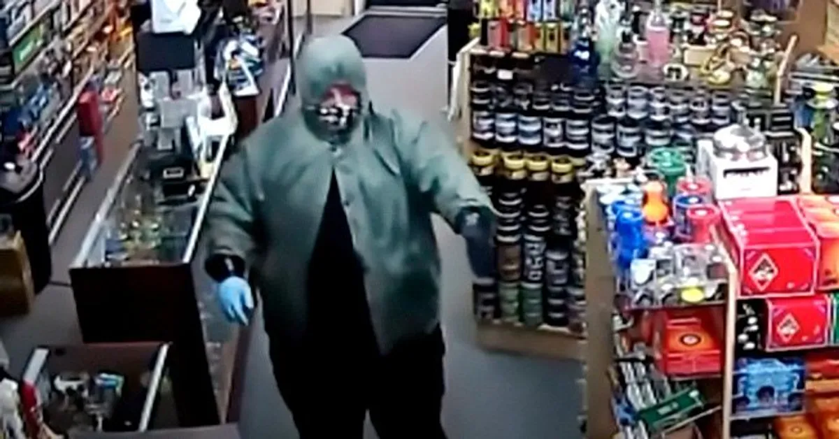 Verkleideter Mann, der in einem Geschäft eine Waffe hochhält. | Quelle: Youtube.com/WNCNTV