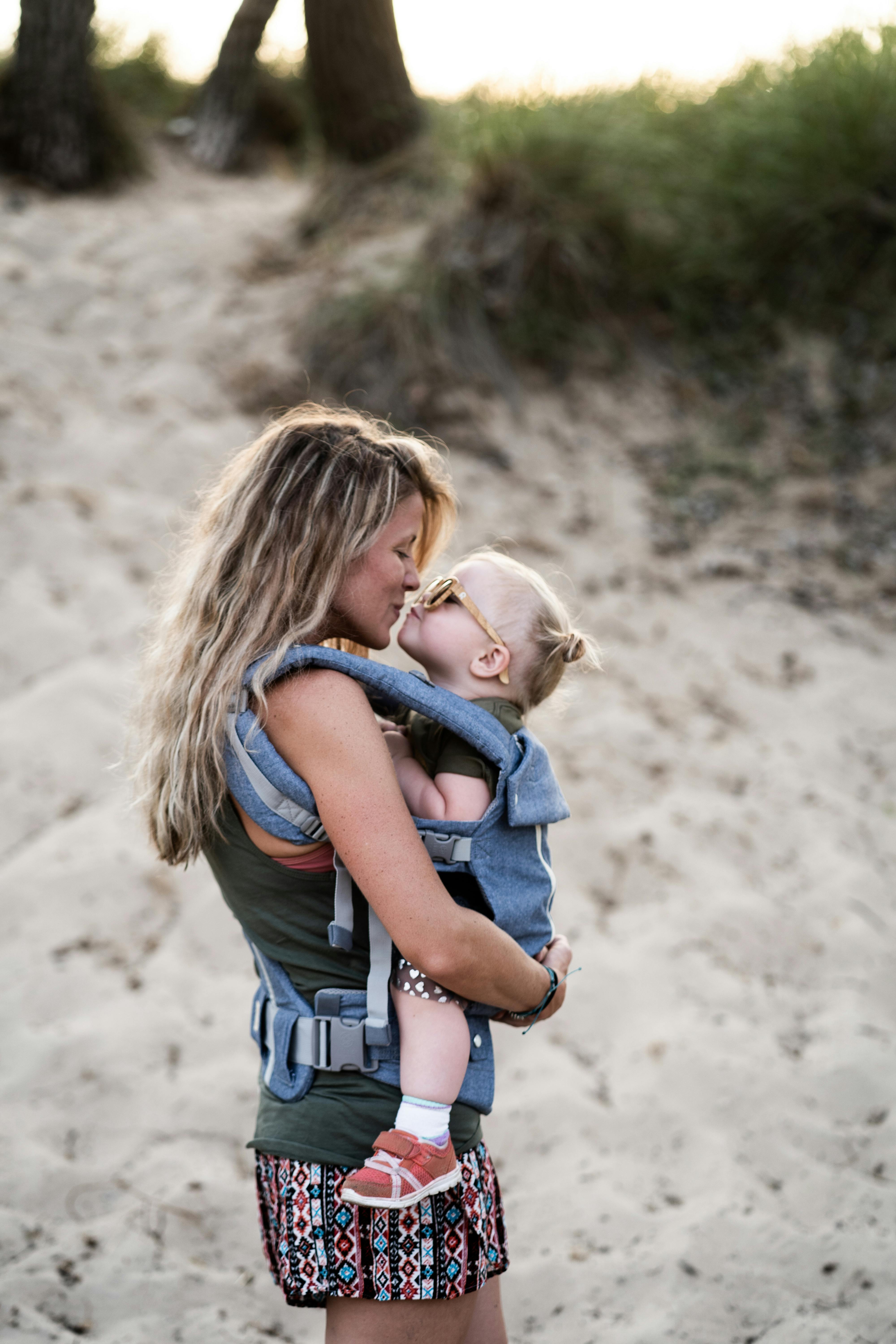 Eine Frau teilt einen Kuss mit einem Kleinkind am Strand | Quelle: Pexels