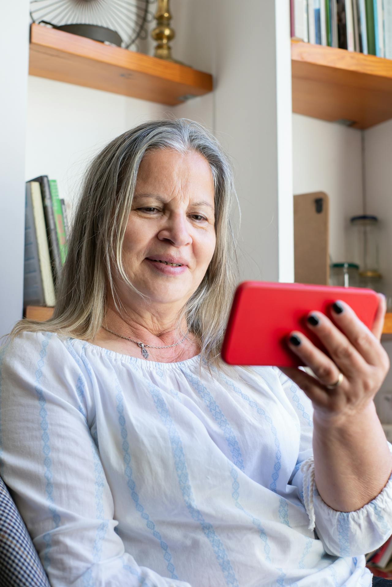 Eine ältere Frau schaut auf ihr Telefon und lächelt | Quelle: Pexels