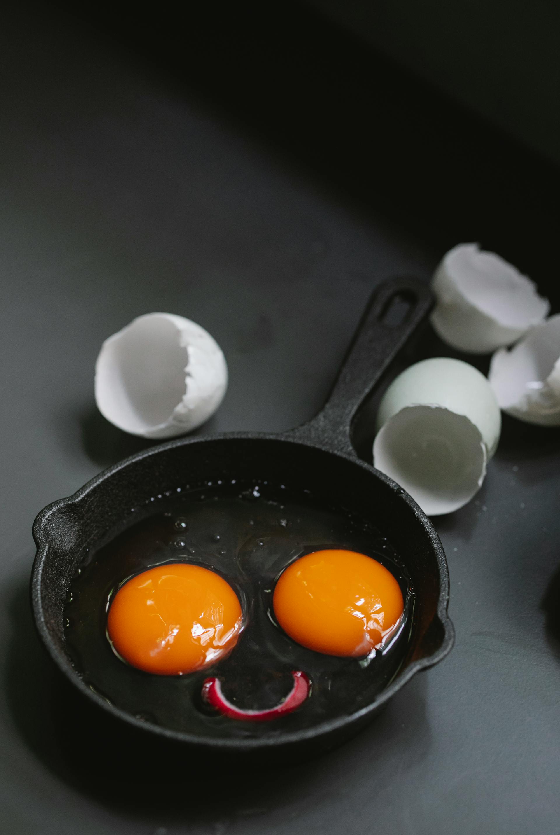 Eine Bratpfanne mit Eigelb, das ein lustiges Gesicht bildet | Quelle: Pexels