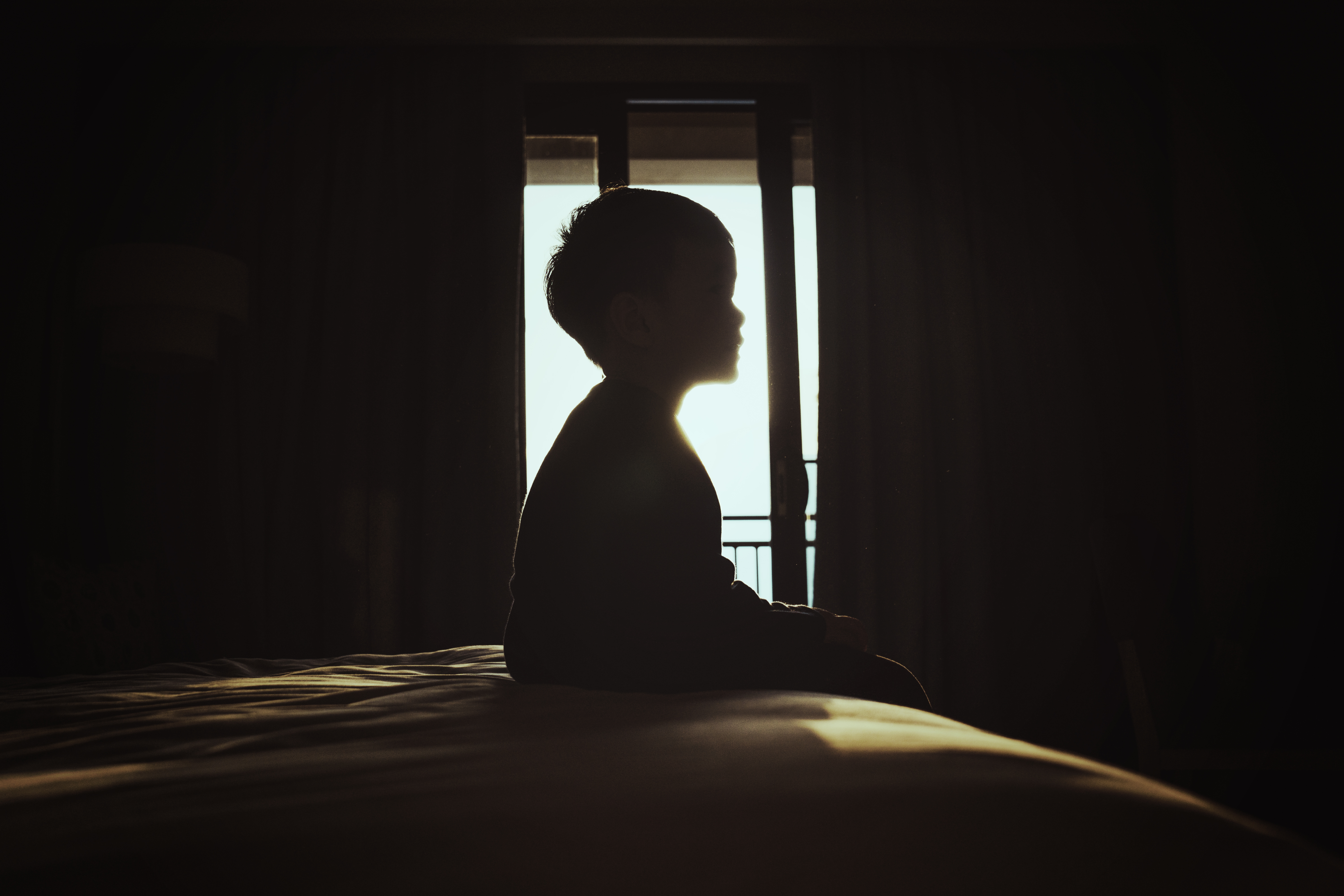 Silhouette eines Jungen, der auf einem Bett sitzt | Quelle: Getty Images