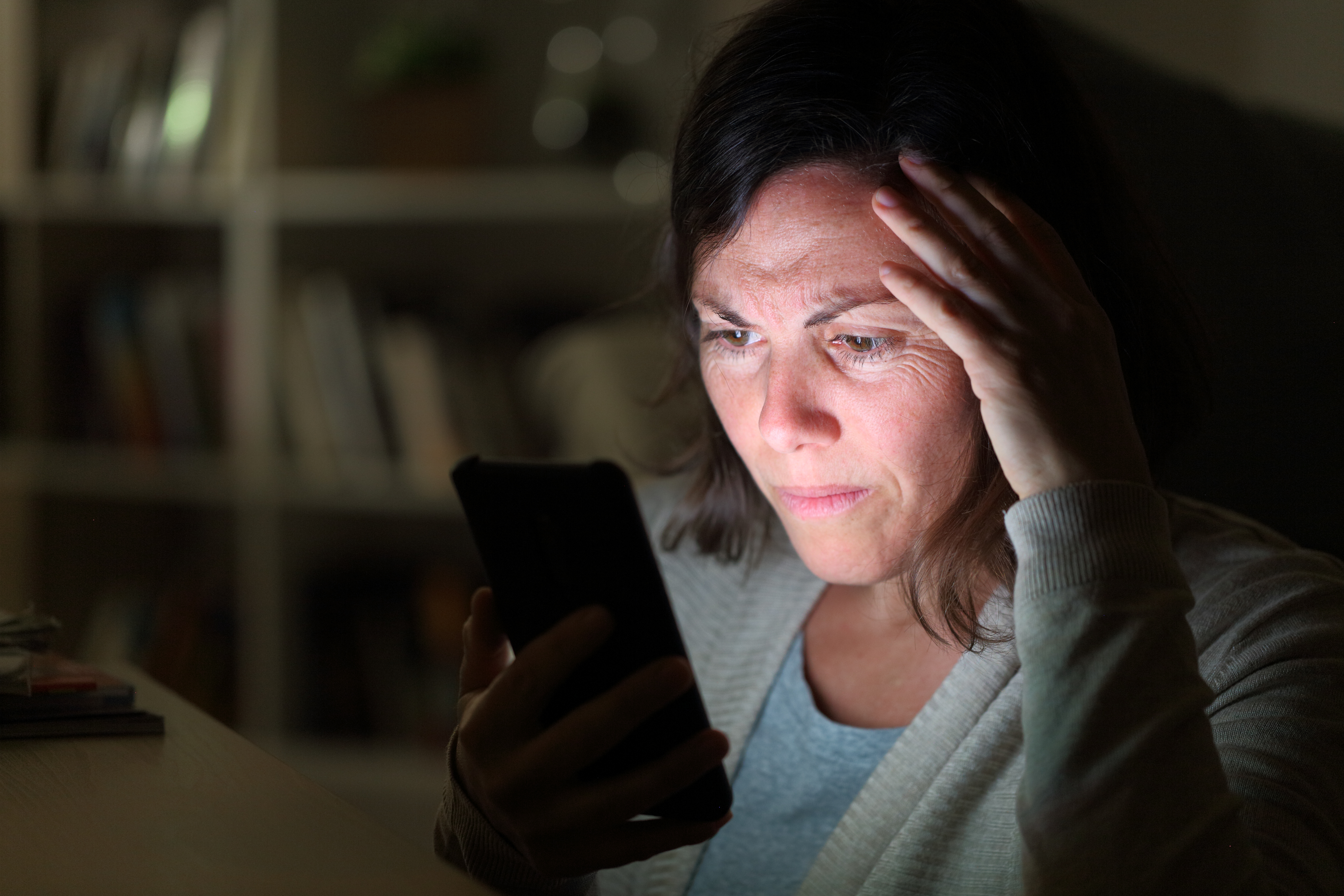 Eine besorgte Frau schaut auf ihr Handy | Quelle: Shutterstock