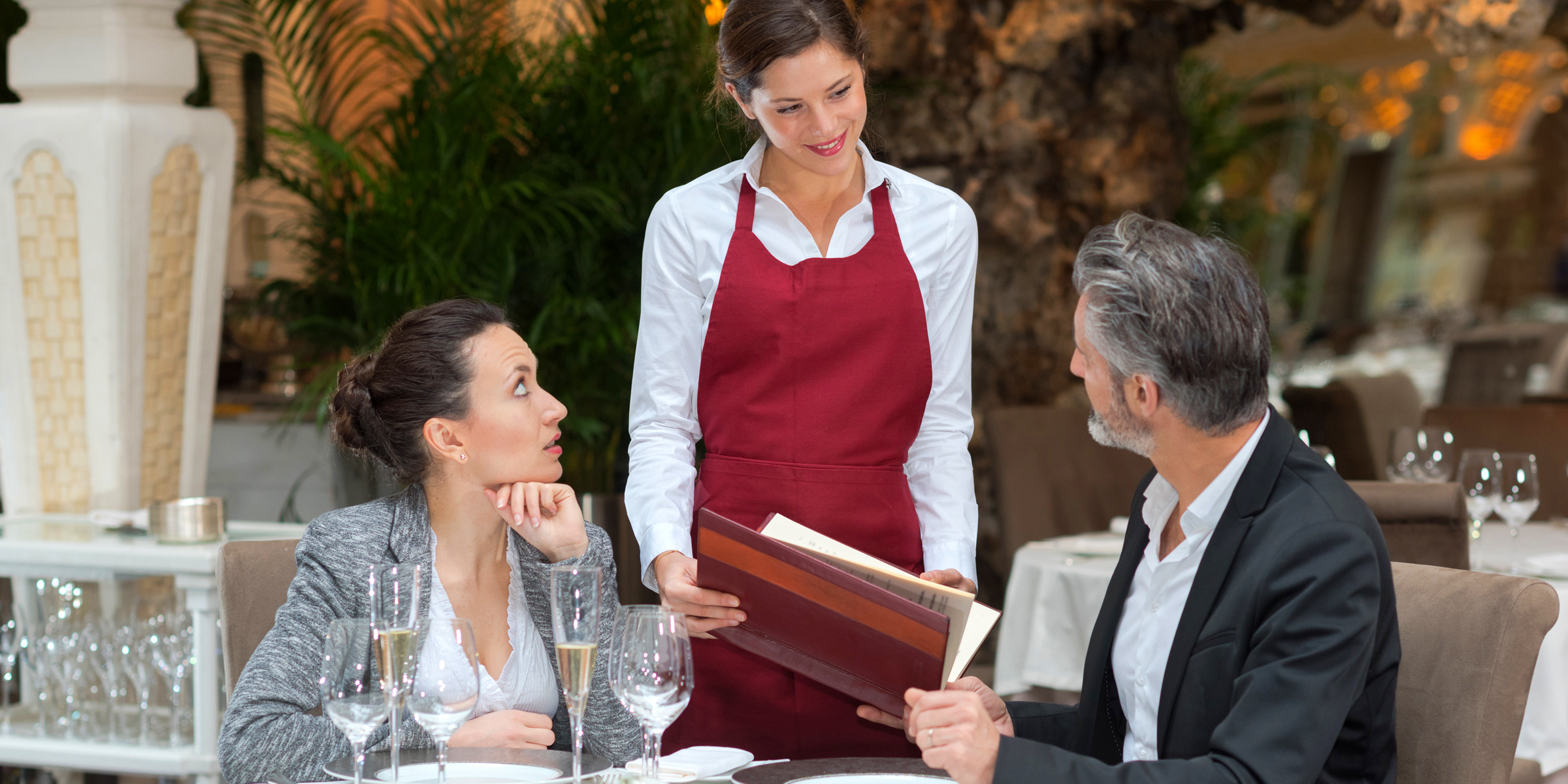 Ein Paar in einem Restaurant mit einer Kellnerin | Quelle: Shutterstock