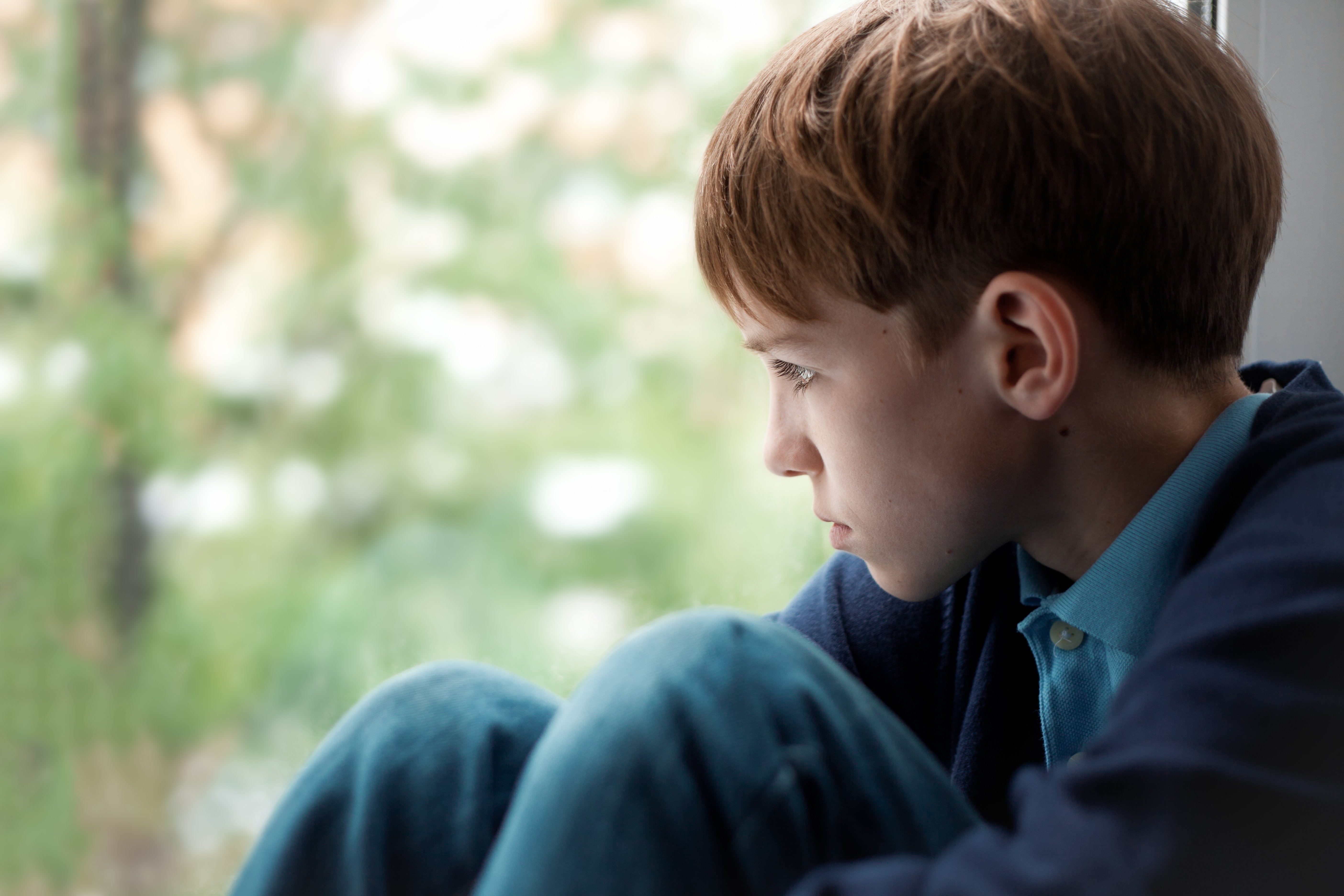Trauriger Teenager sitzt am Fenster | Quelle: Shutterstock