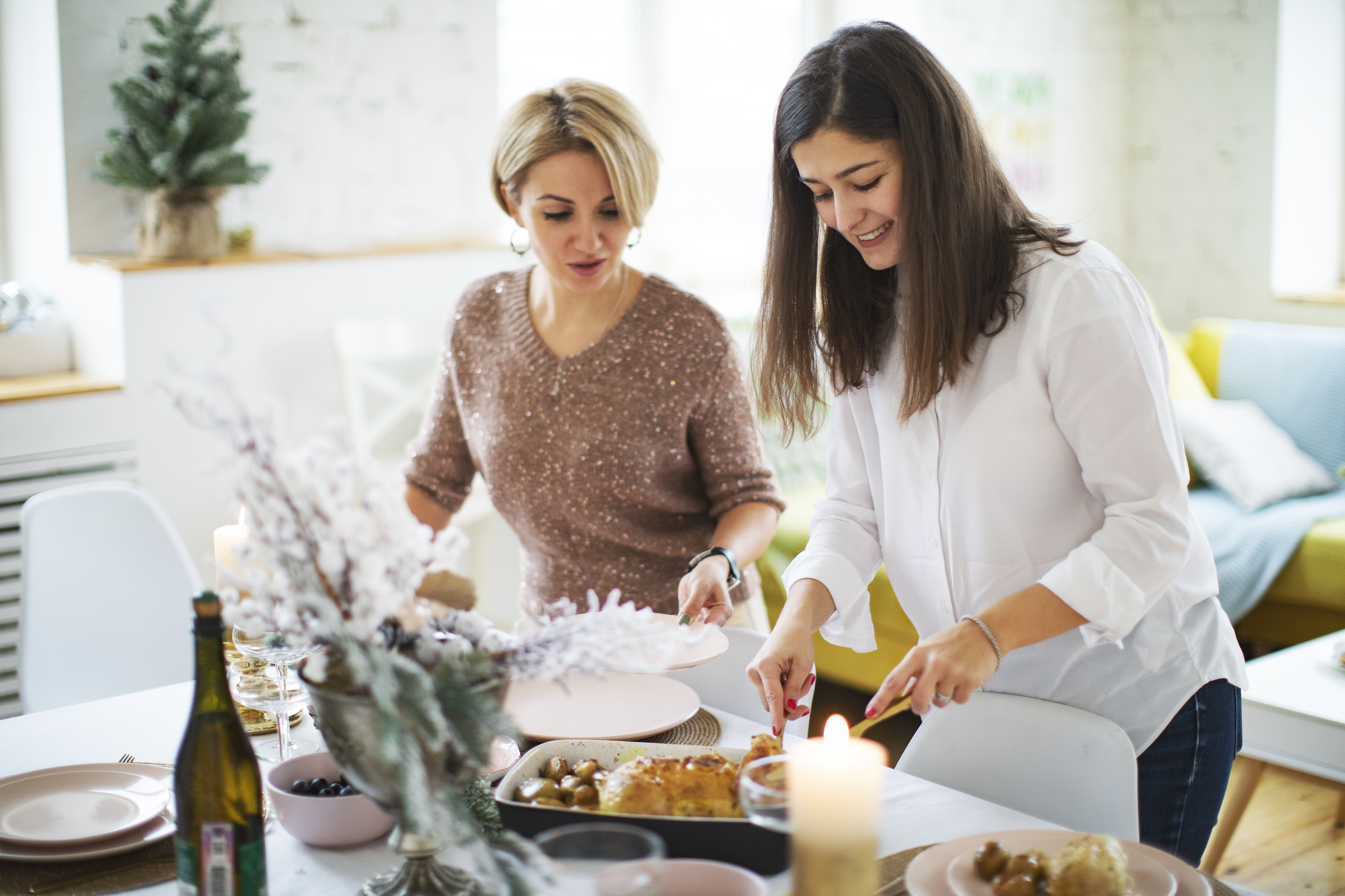 Freundinnen decken den Tisch vor der Weihnachtsfeier | Quelle: Getty Images