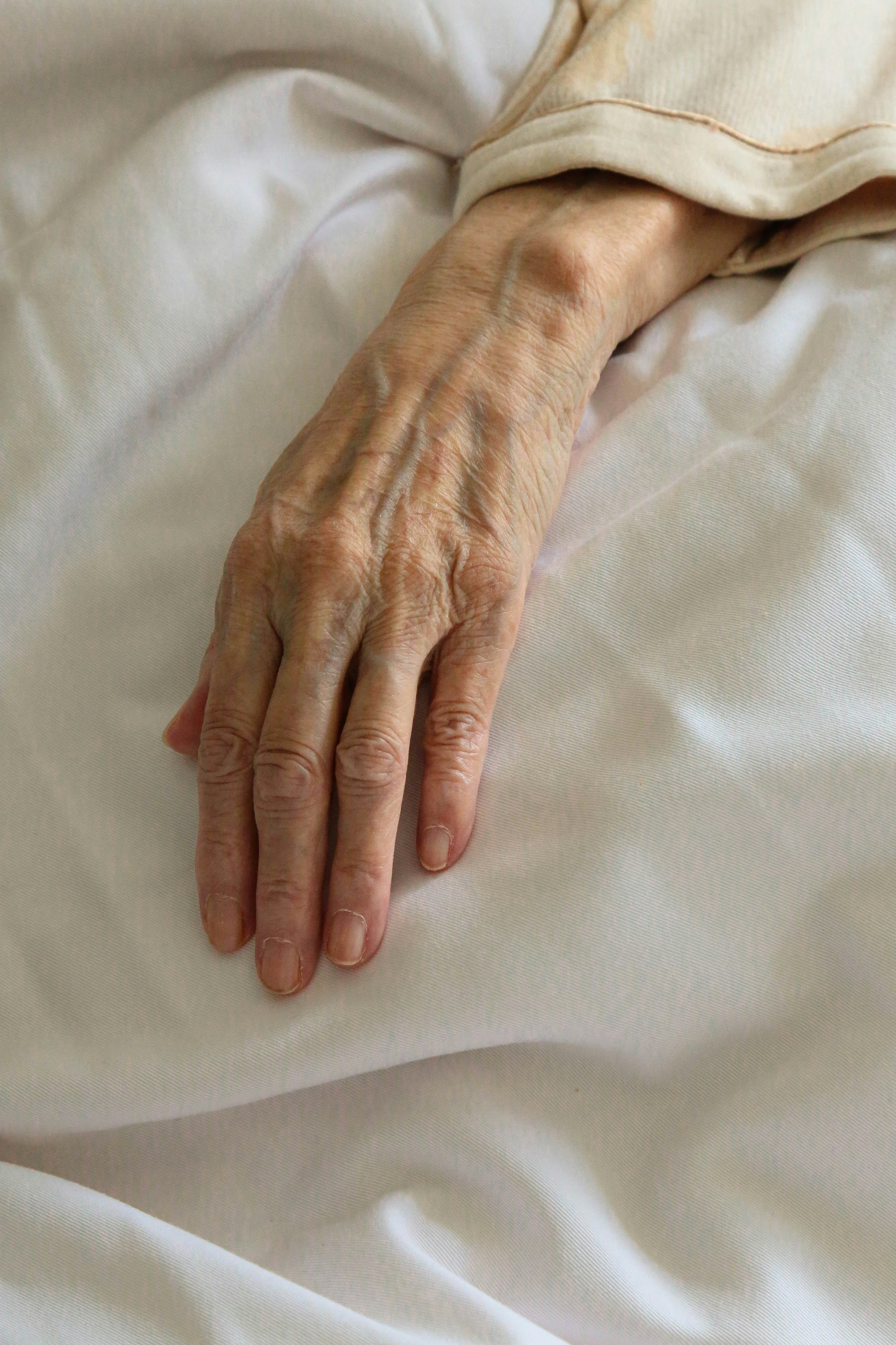 Die Hand einer kranken Frau auf einem Bett | Quelle: Unsplash