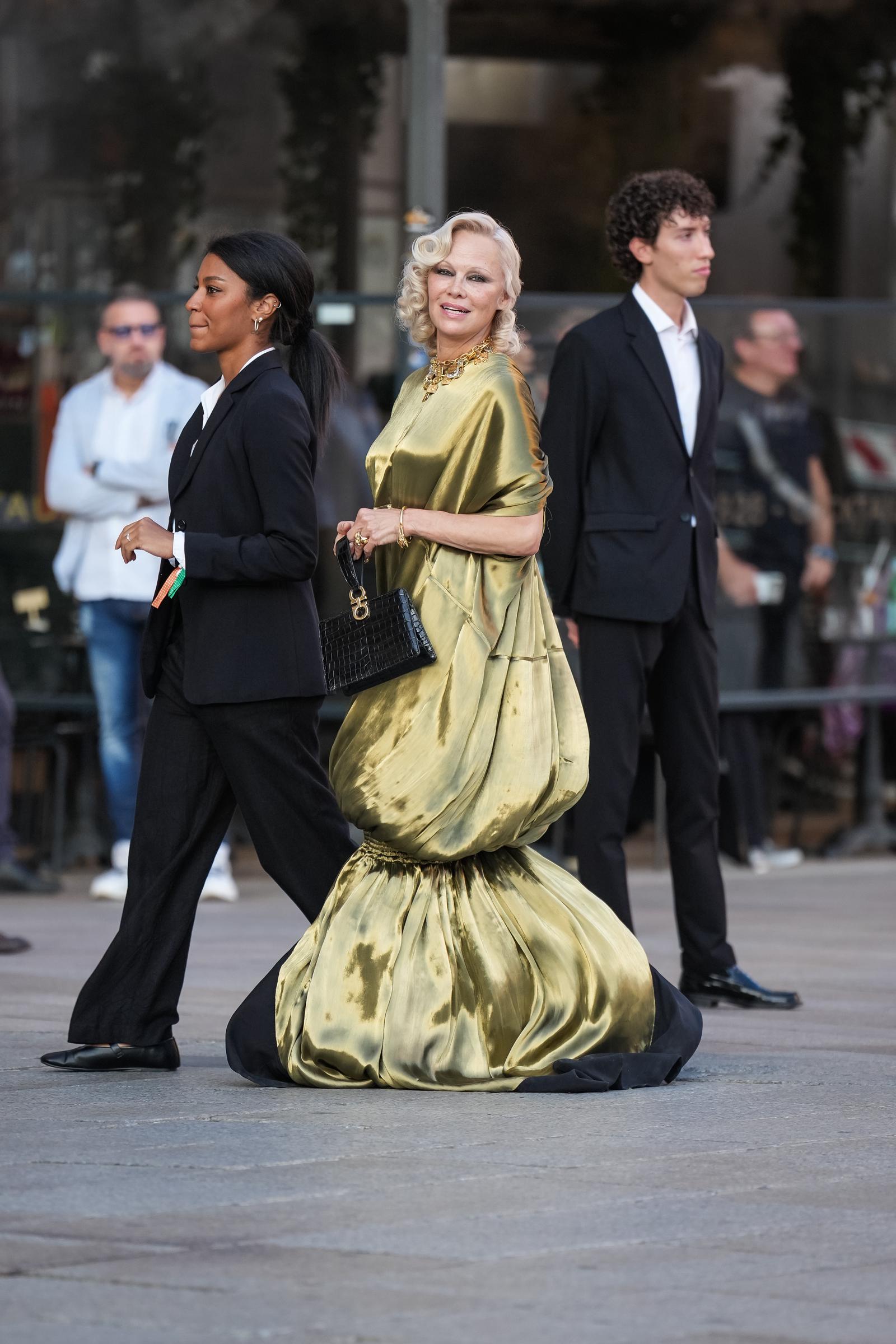 Pamela Anderson kommt am 22. September 2026 während der Mailänder Modewoche in einem bodenlangen, metallisch-goldenen Abendkleid an. Zu dem Outfit trug sie außerdem eine klobige goldene Halskette und eine strukturierte schwarze Handtasche. | Quelle: Getty Images