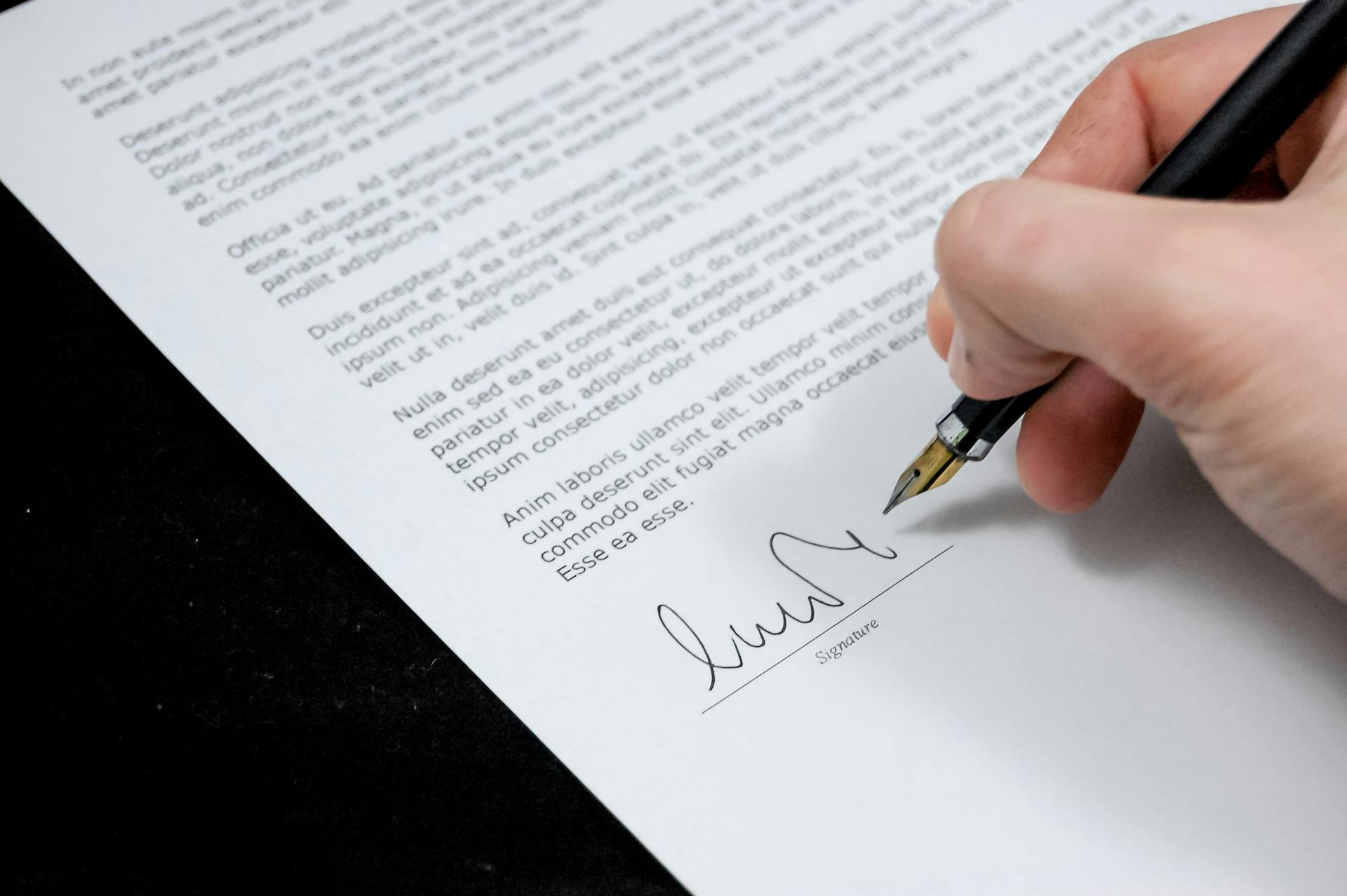 Eine Person beim Unterschreiben von Papierkram | Quelle: Pexels