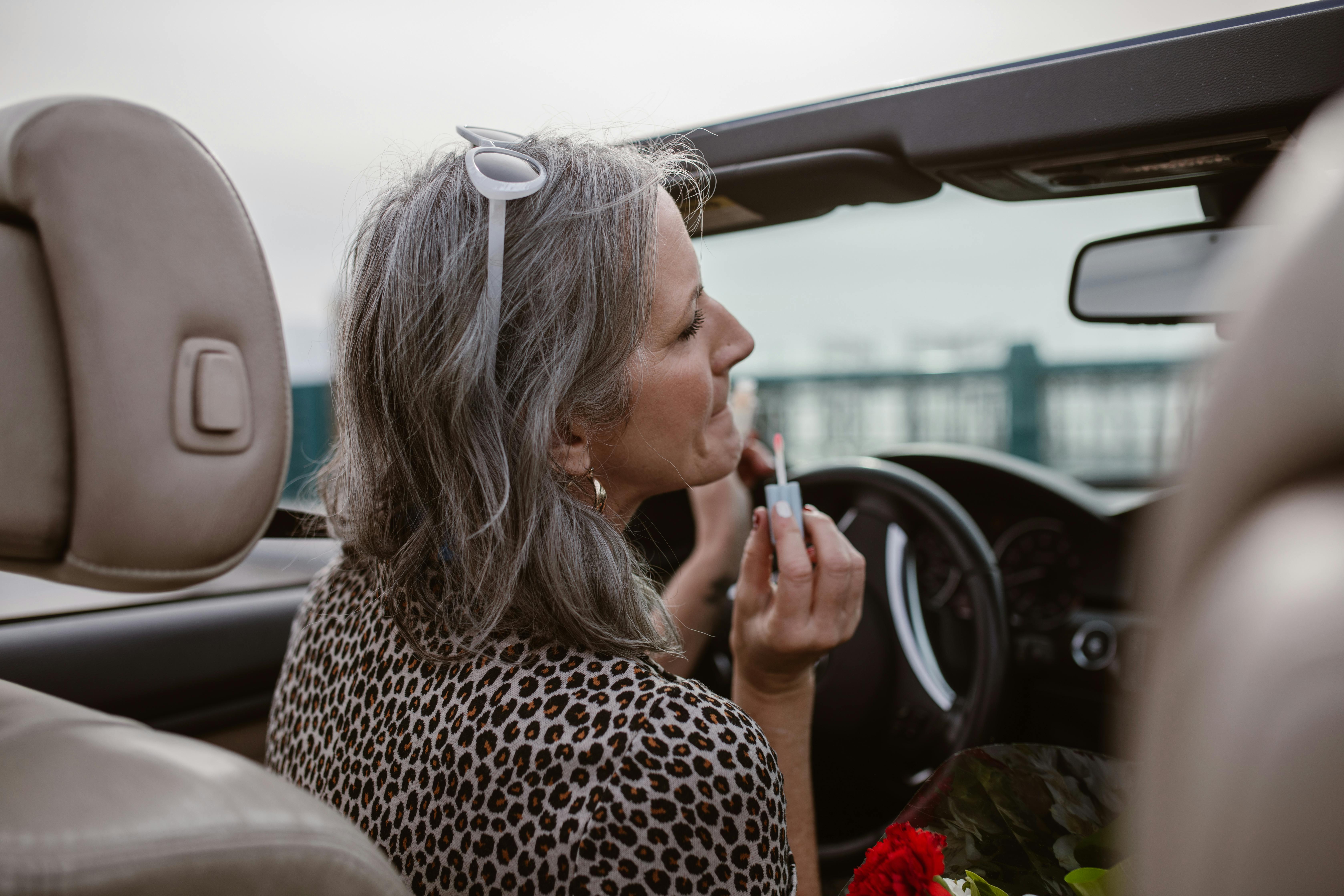 Eine Frau trägt über den Rückspiegel ihres Autos Lippenbalsam auf | Quelle: Pexels