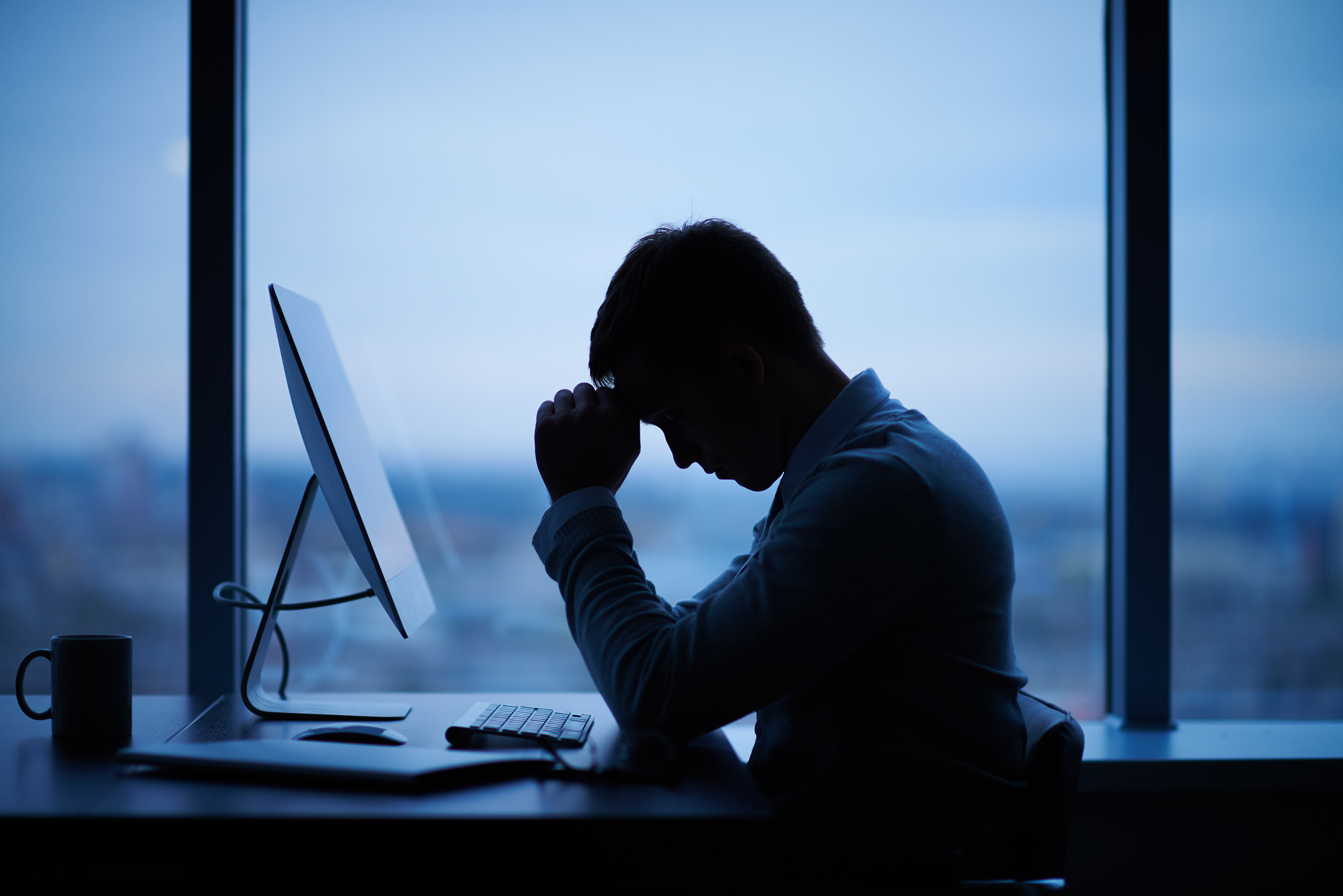 Müder Mann sitzt vor einem Computer im Büro | Quelle: Shutterstock