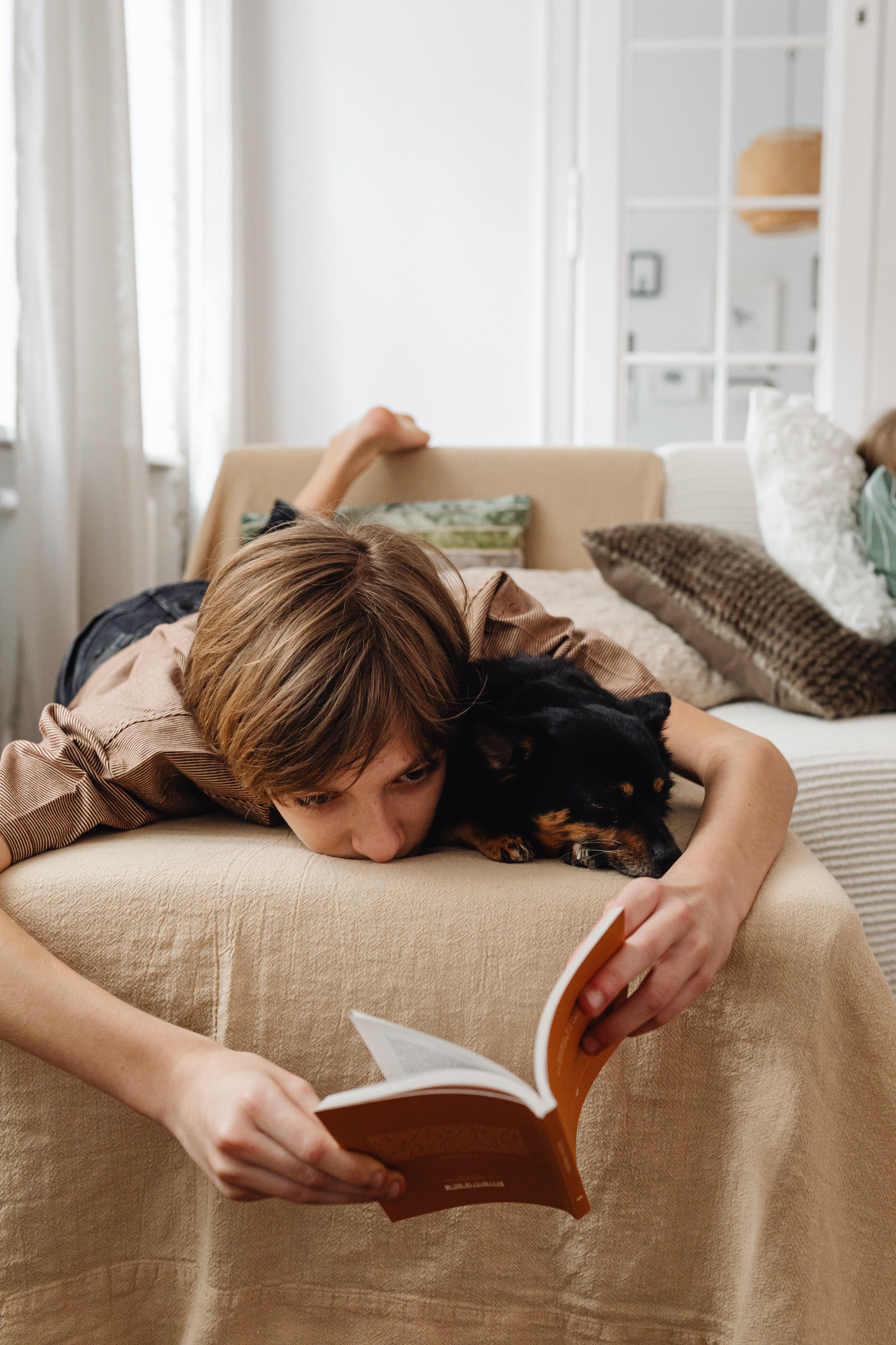 Ein kleiner Junge liest mit seinem Hund ein Buch, während er auf seinem Bett liegt | Quelle: Pexels