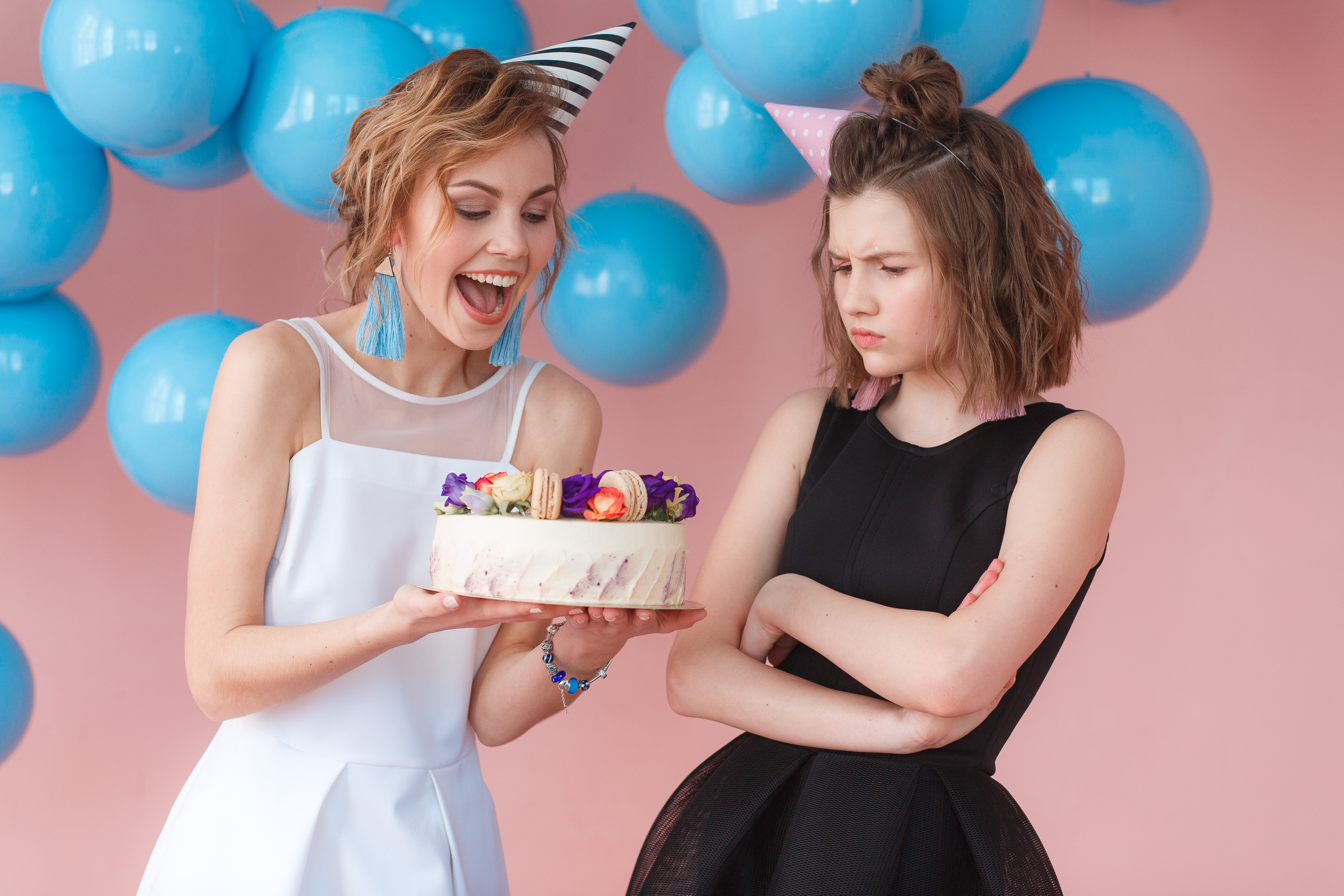 Zwei Teenager halten eine Geburtstagstorte, einer lächelt, der andere runzelt die Stirn | Quelle: freepic.diller auf Freepik