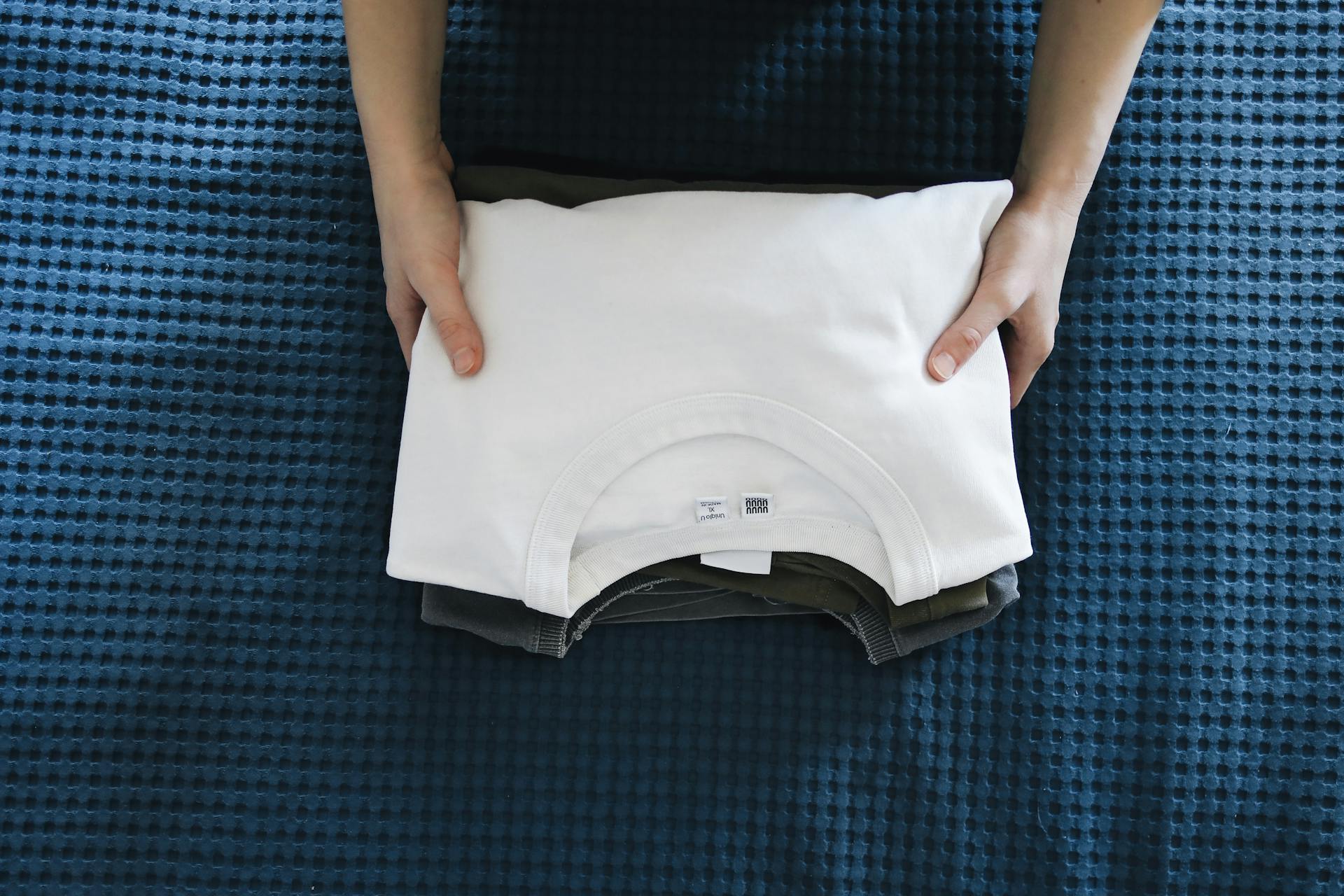 Eine Person mit gefalteten T-Shirts | Quelle: Pexels