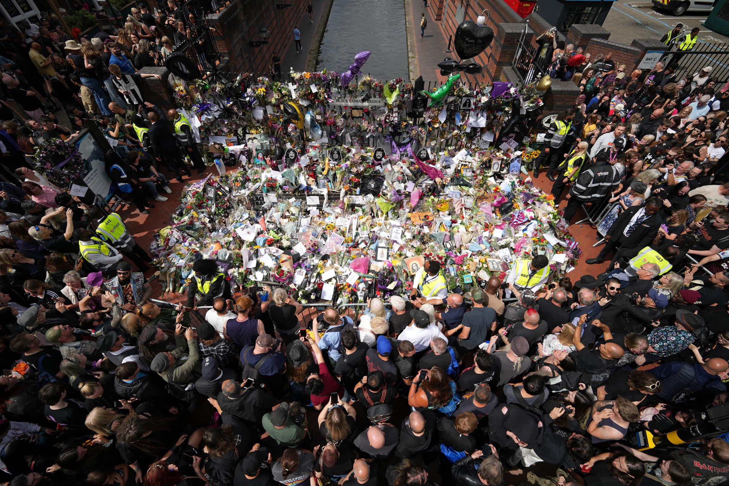 Fans sehen sich die Ehrungen für den verstorbenen Ozzy Osbourne an der Black Sabbath Bench and Bridge an, während sein Leichenzug am 30. Juli 2025 in Birmingham, England, durch die Stadt fährt | Quelle: Getty Images