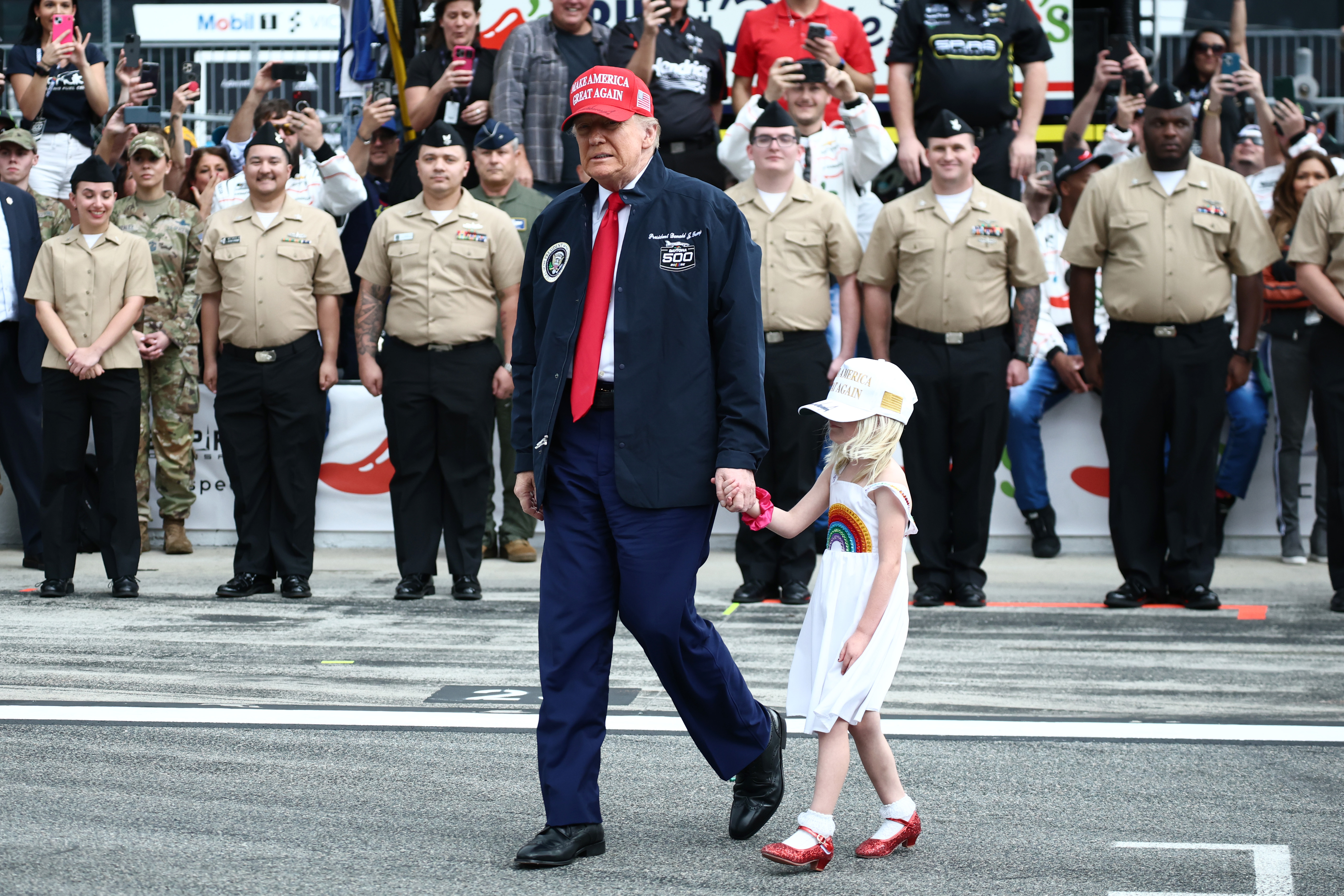 US-Präsident Donald Trump und seine Enkelin gehen vor dem NASCAR Cup Series Daytona 500 auf dem Daytona International Speedway am 16. Februar 2025 in Daytona Beach, Florida, auf die Startaufstellung | Quelle: Getty Images