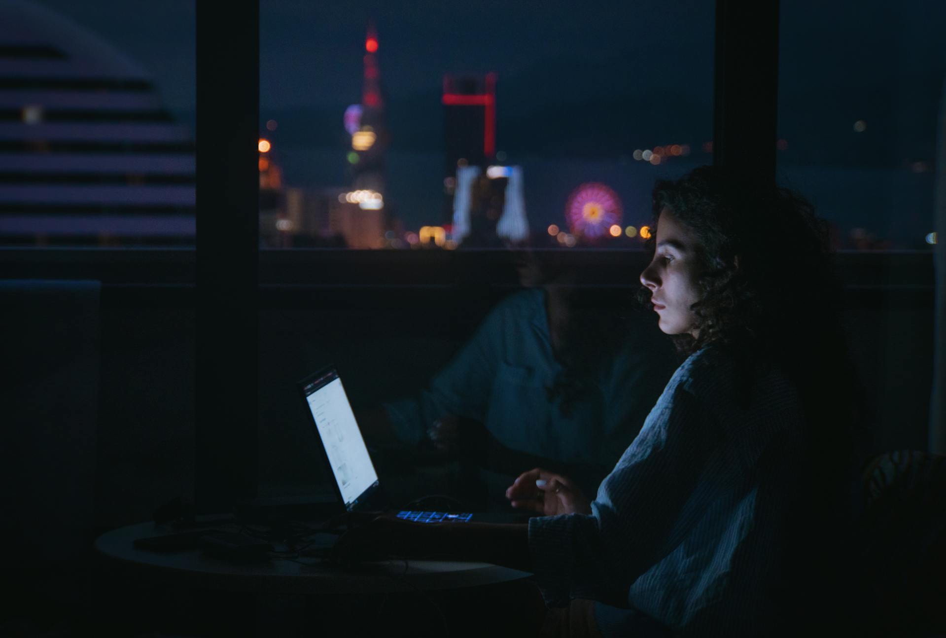 Eine Frau benutzt ihren Laptop in der Dunkelheit | Quelle: Pexels