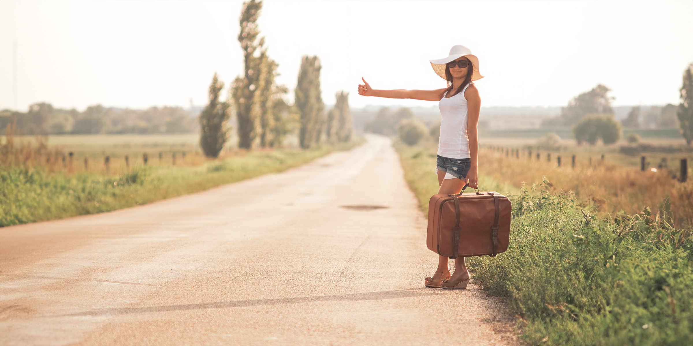 Junge Frau mit einem Koffer auf einer Straße | Quelle: Shutterstock