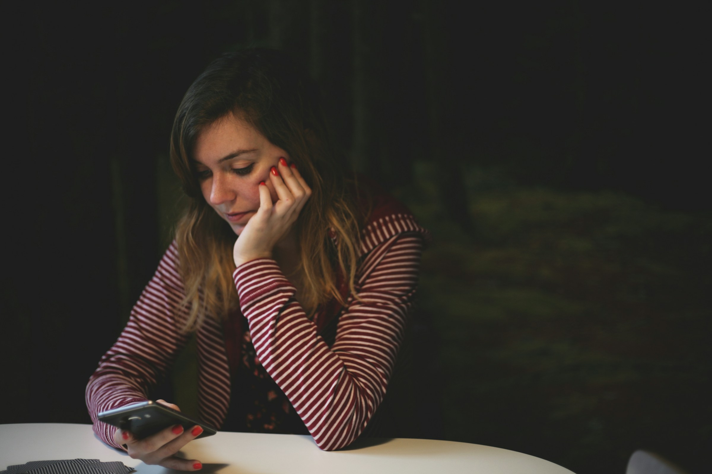 Junge Frau starrt nachdenklich auf ihr Telefon | Quelle: Unsplash