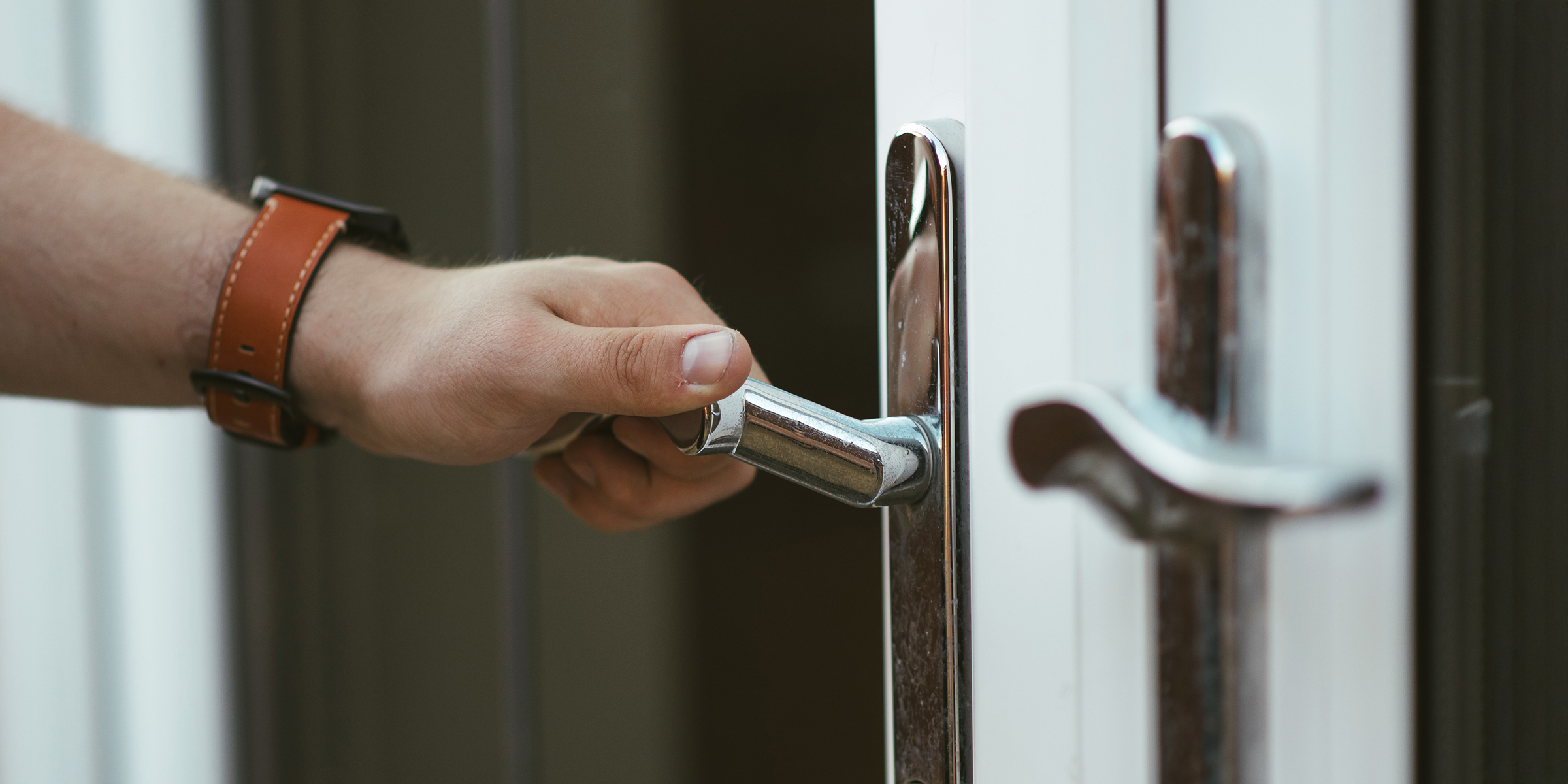 Die Hand eines Mannes, die einen silbernen Türgriff umklammert | Quelle: Shutterstock