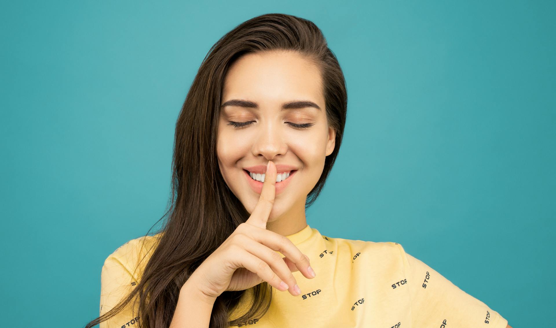 Eine lächelnde Frau, die einen Finger auf ihre Lippen presst | Quelle: Pexels