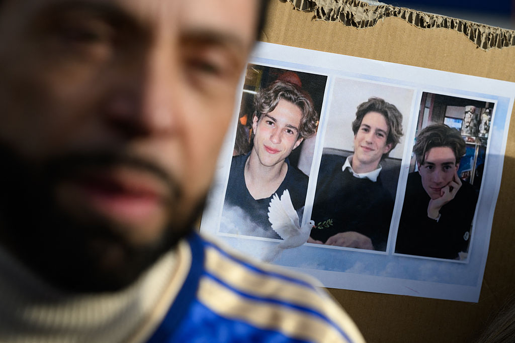 Dieses Foto zeigt ein Poster mit Porträtfotos des Opfers Trystan und seines Vaters Christian Pidoux im Vordergrund, während er an einem Schweigemarsch teilnimmt, der am 31. Januar 2026 in Lutry bei Lausanne zum Gedenken an einige der Opfer des tödlichen Silvesterbrands in Crans-Montana organisiert wurde | Quelle: Getty Images