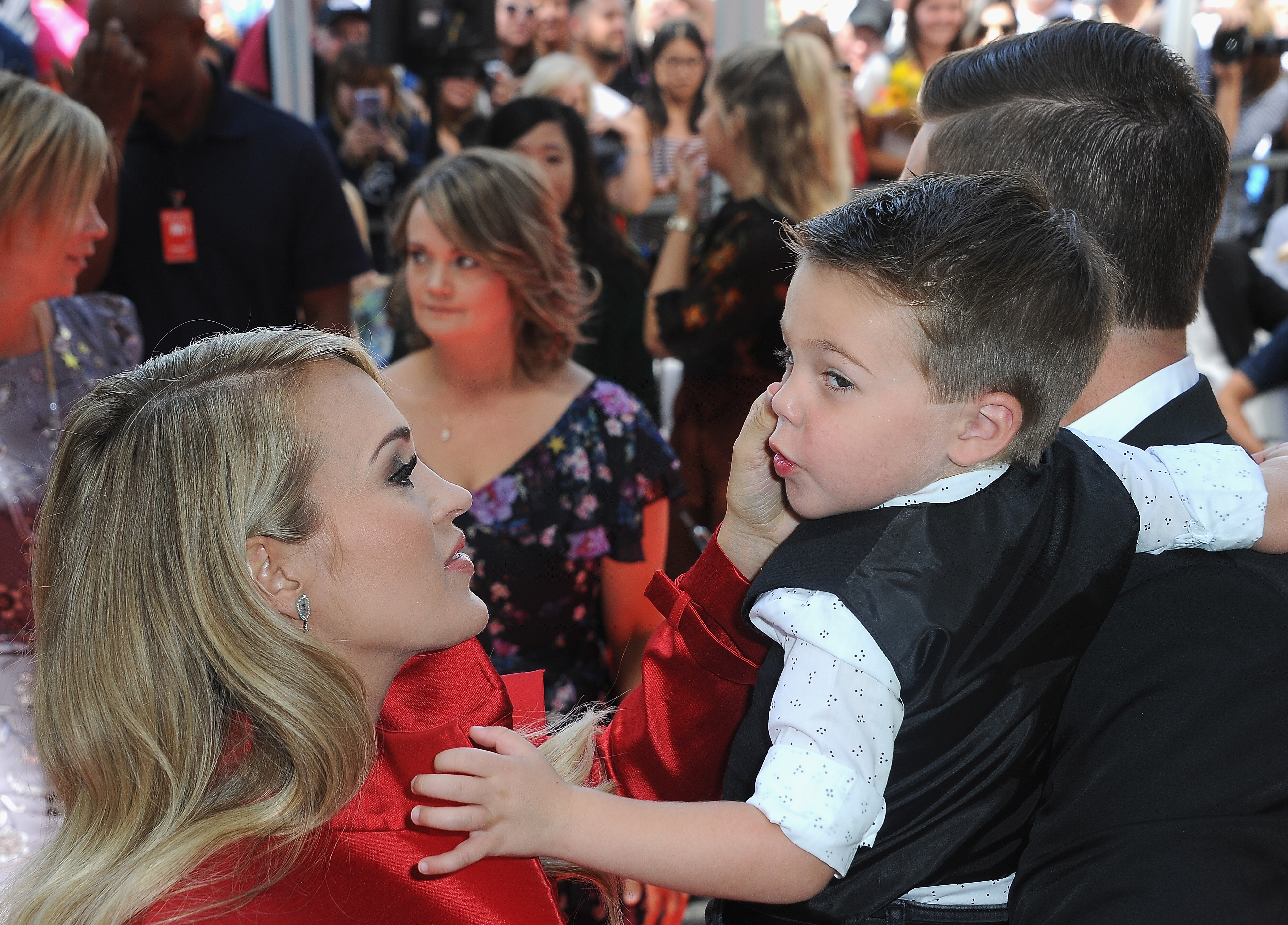 Carrie Underwood genießt einen zärtlichen Moment mit ihrem ältesten Sohn Isaiah, während ihr Mann Mike Fisher ihn bei einer Veranstaltung im Jahr 2018 im Arm hält. Carrie und Mike haben im Januar 2019 ihren zweiten Sohn, Jacob, willkommen geheißen. | Quelle: Getty Images.