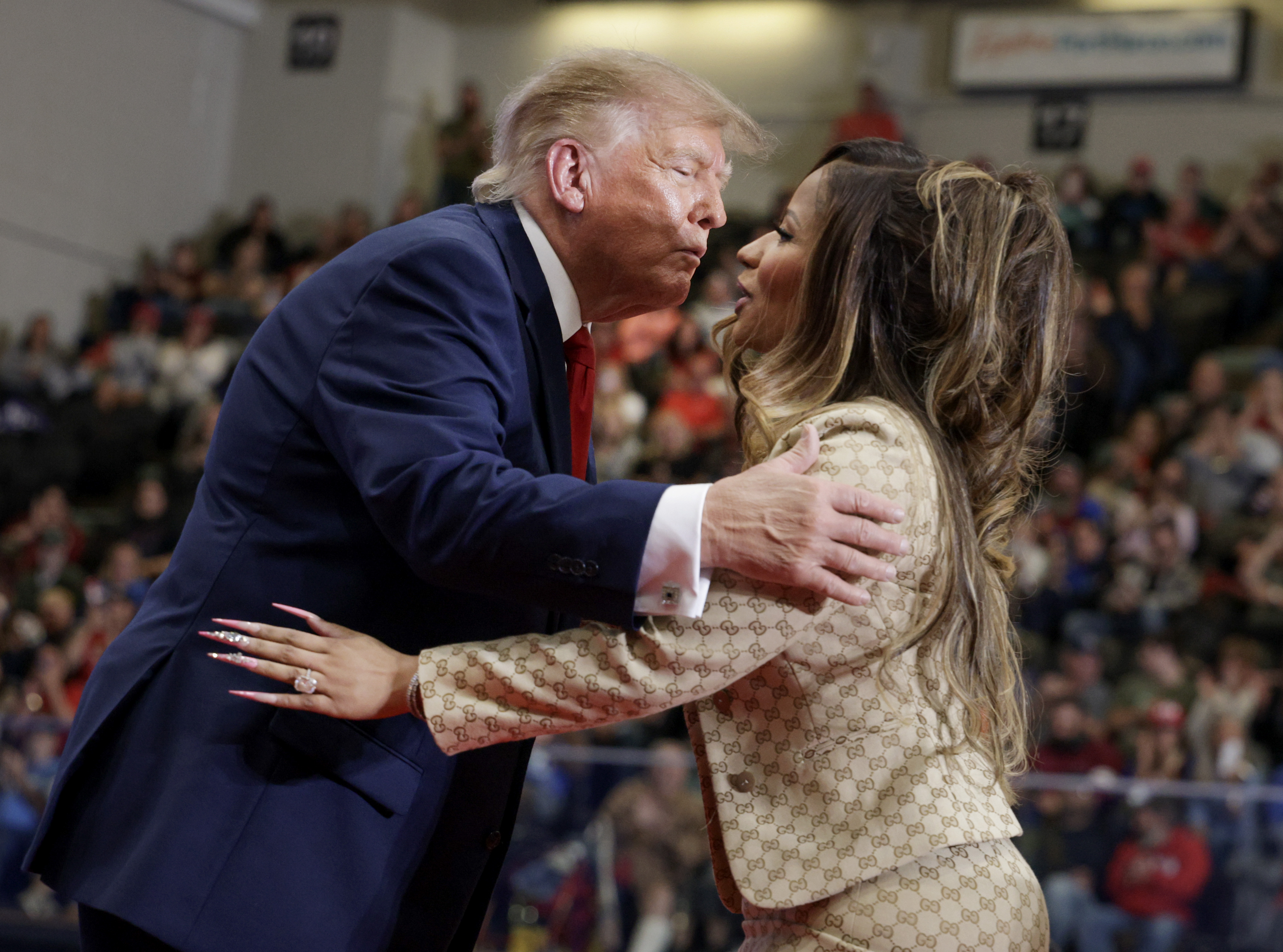 Donald Trump beugt sich mit zusammengepressten Lippen vor, als er Nicki Minaj auf der Bühne begrüßt; ihre Gesichter berühren sich fast, während sie eine Hand auf seine Jacke legt – ein besonders eindrucksvoller Moment ihrer viel diskutierten Begegnung. | Quelle: Getty Images
