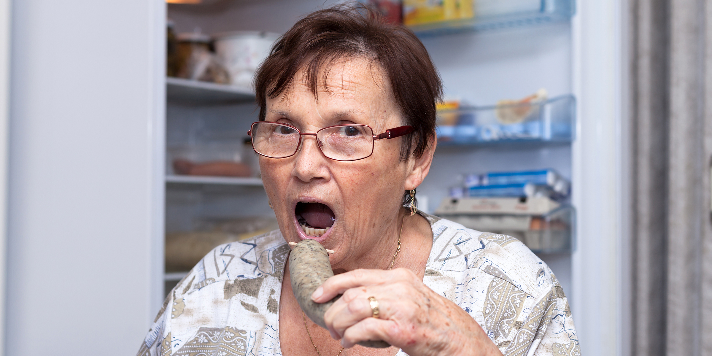 Eine Frau beim Essen vor dem Kühlschrank | Quelle: Shutterstock