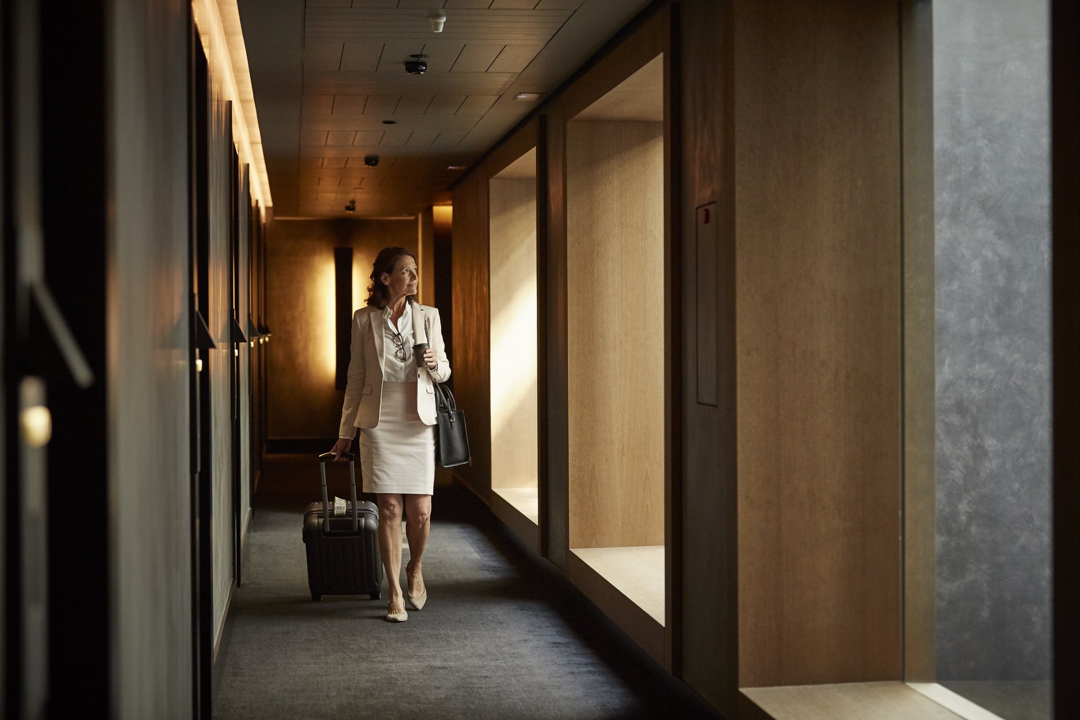 Geschäftsfrau mit Koffer am Hotelkorridor. I Quelle: Getty Images